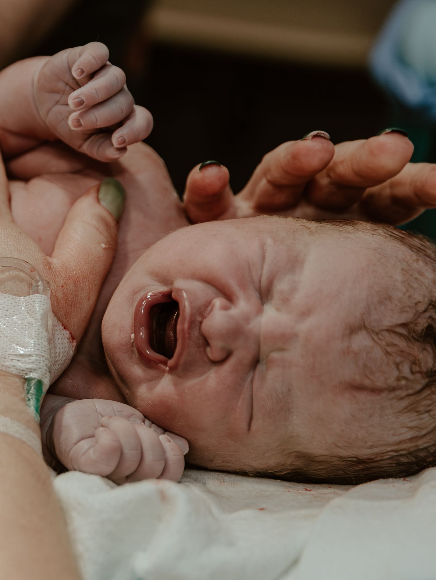 Newborn baby crying during their first moments after birth in hospital setting.
