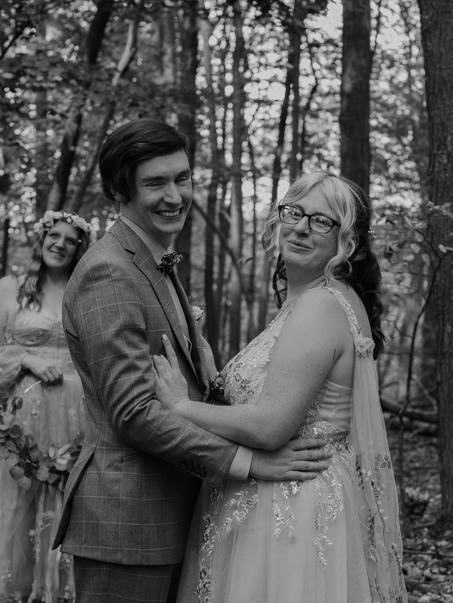 Candid black and white photos capture joyful laughter between newlyweds during a forest wedding.