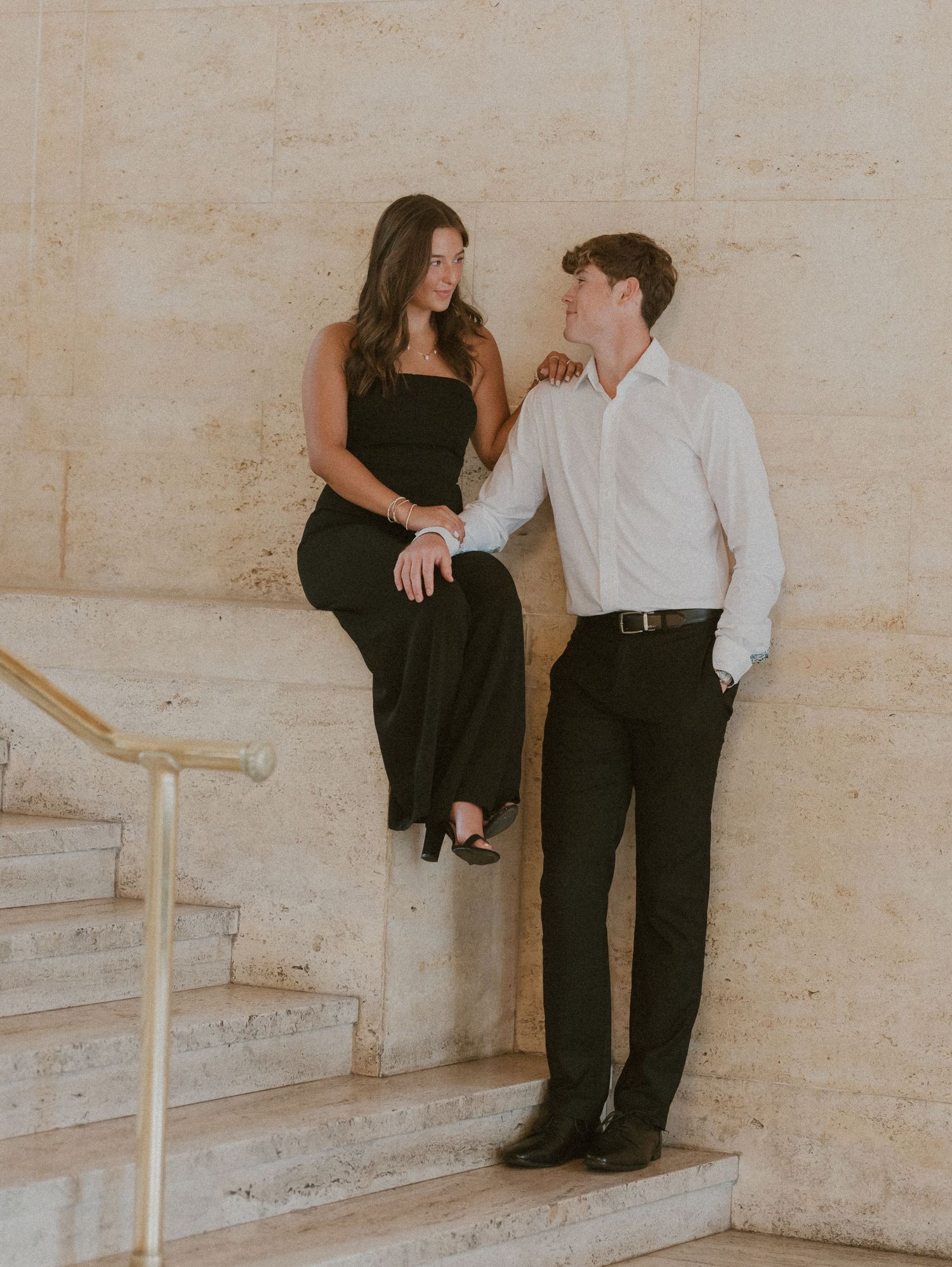 A couple in contrasting outfits poses together on rustic stone steps during an engagement session.