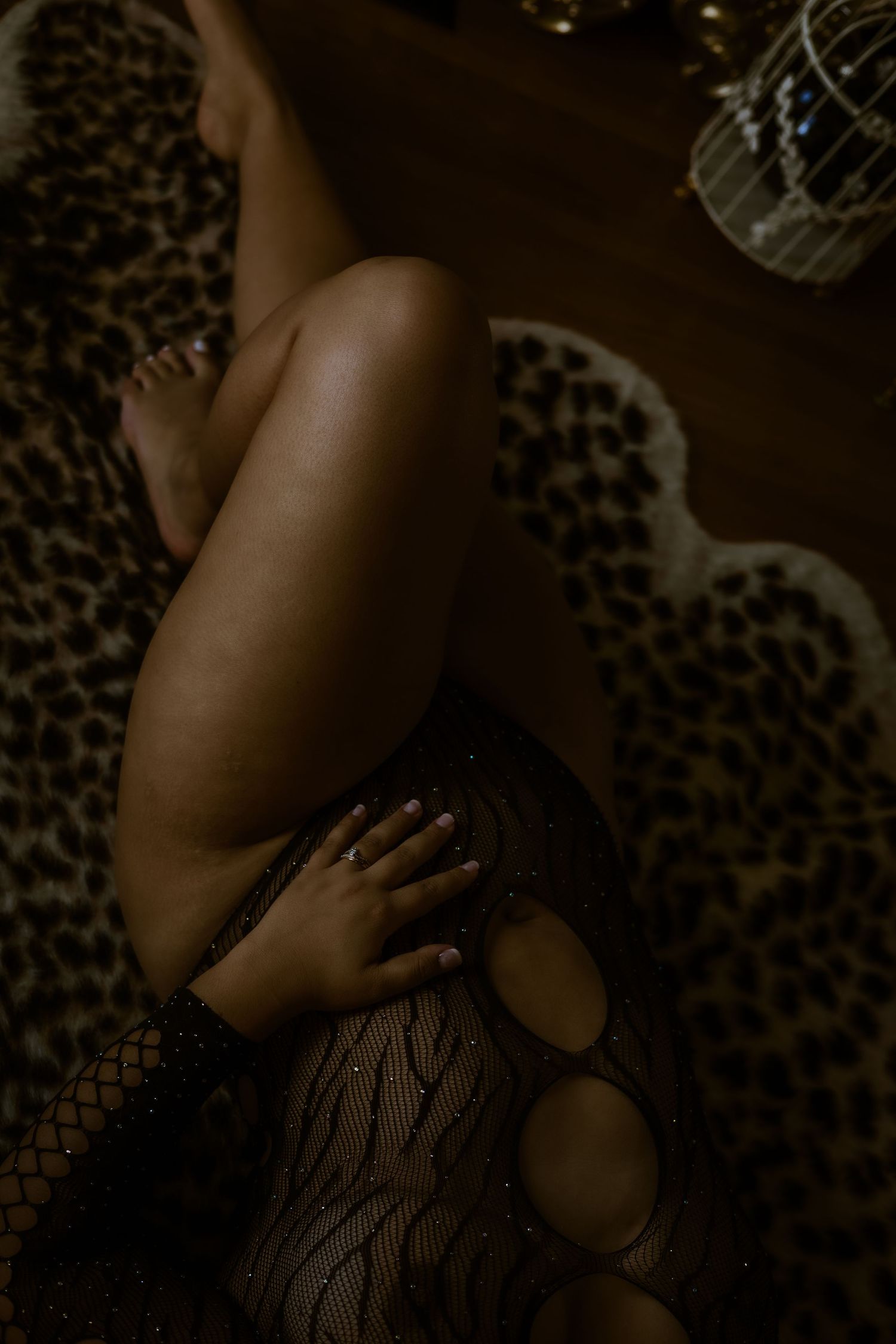 Artistic boudoir photo showing dark lace lingerie against leopard print fabric in moody lighting.