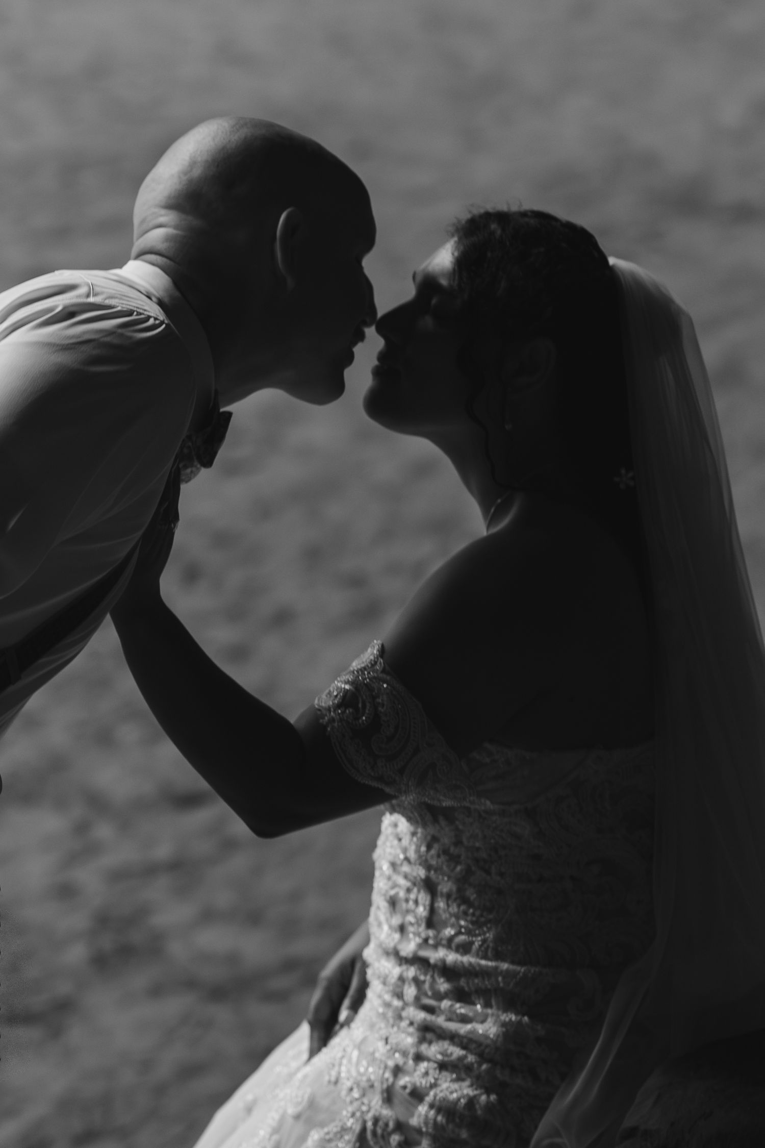 Silhouetted wedding couple sharing a tender moment against a dramatic backdrop.