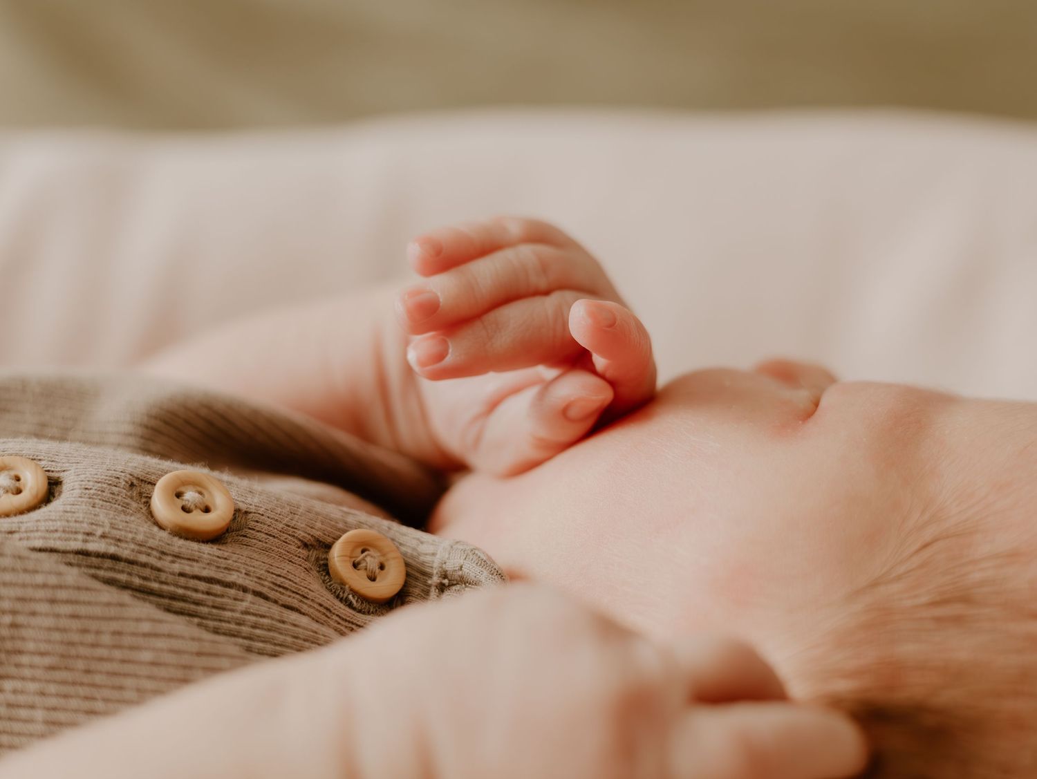 Close-up of tiny baby feet resting on soft white fabric with delicate skin details.