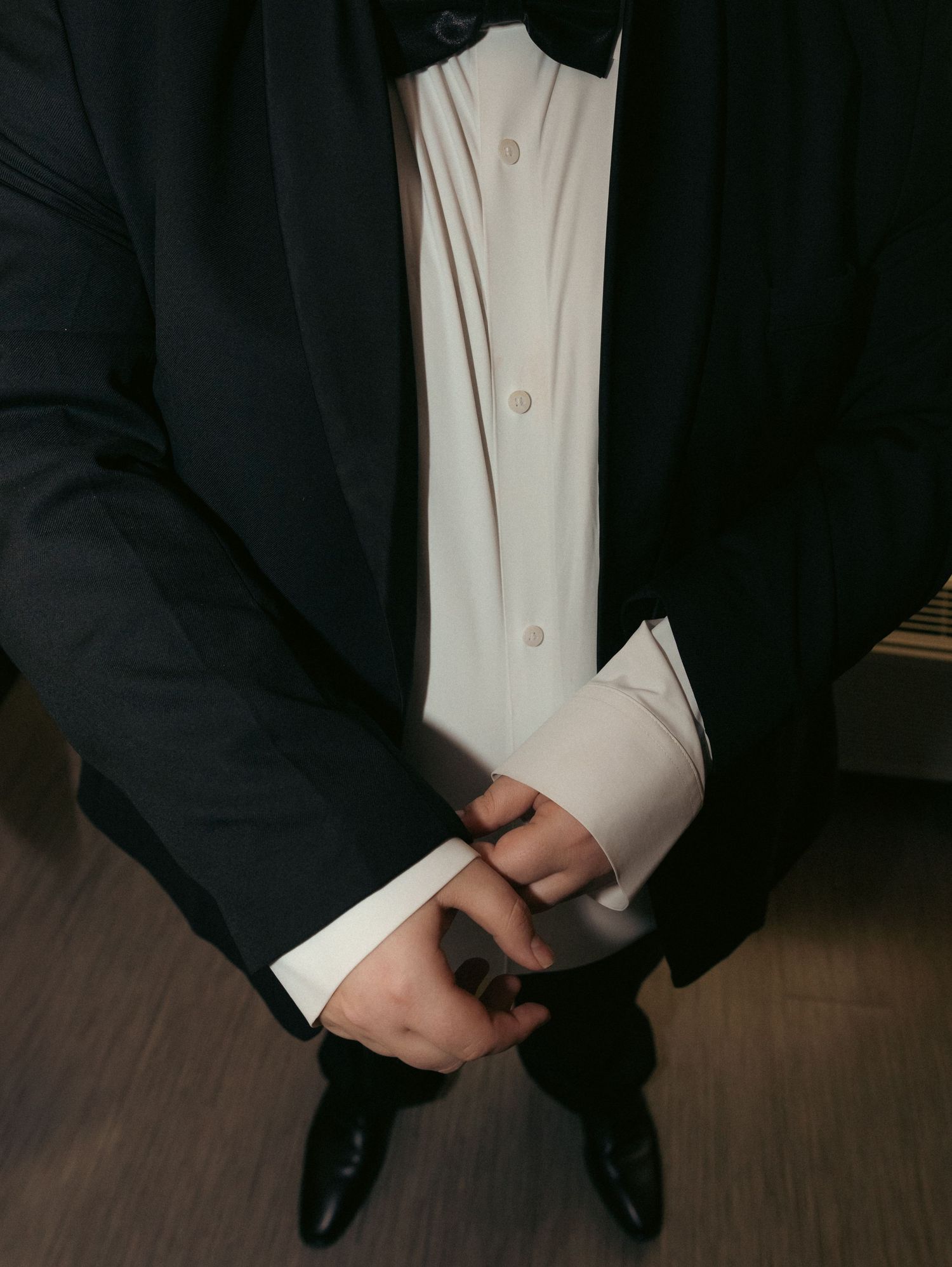 Close-up view of polished black dress shoes with white shirt and dark suit pants.