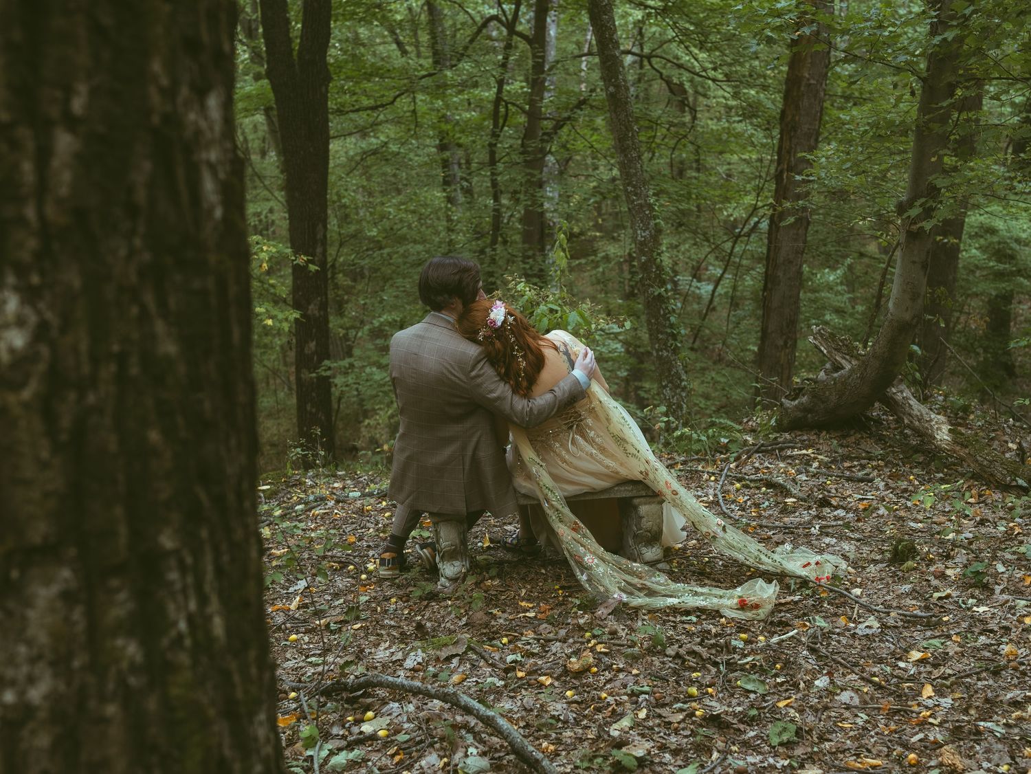 Wedding party gathered in a serene forest setting with fallen autumn leaves.