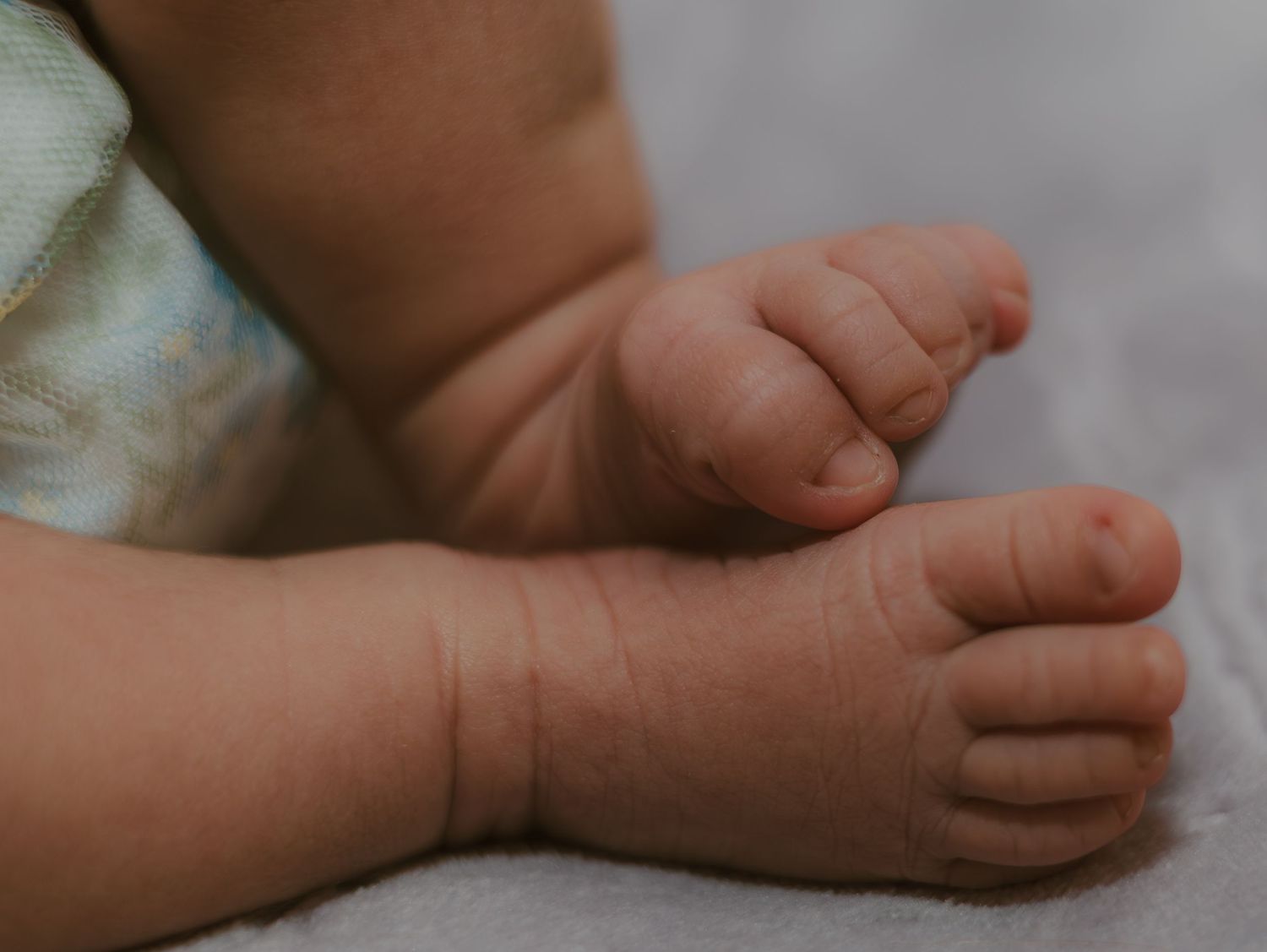 Close-up sequence showing tiny newborn baby feet and hands against a light background.