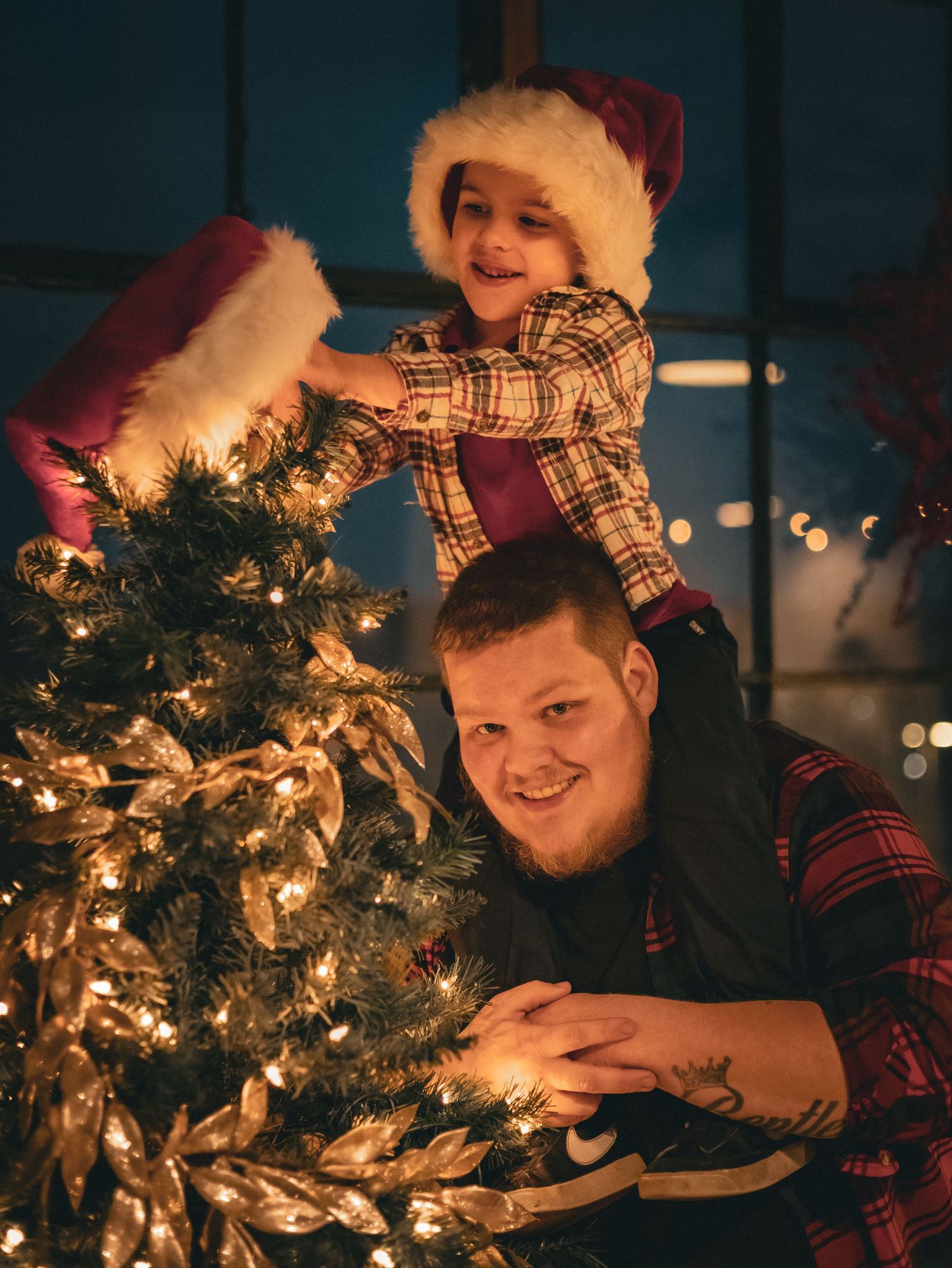 Father and child decorating Christmas tree together with warm lighting.
