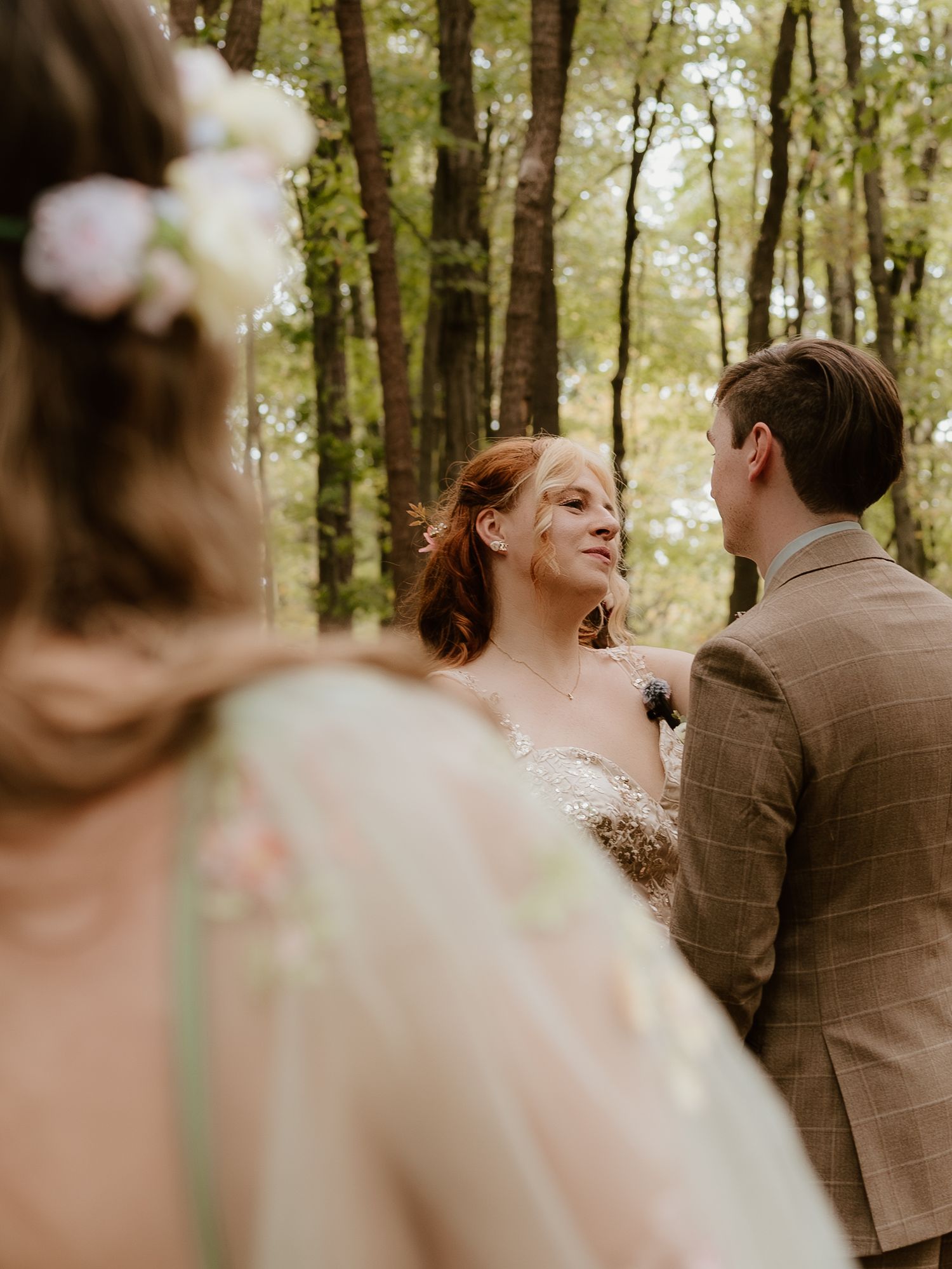 A romantic wedding couple shares an intimate moment in a sunlit forest setting during their special day.