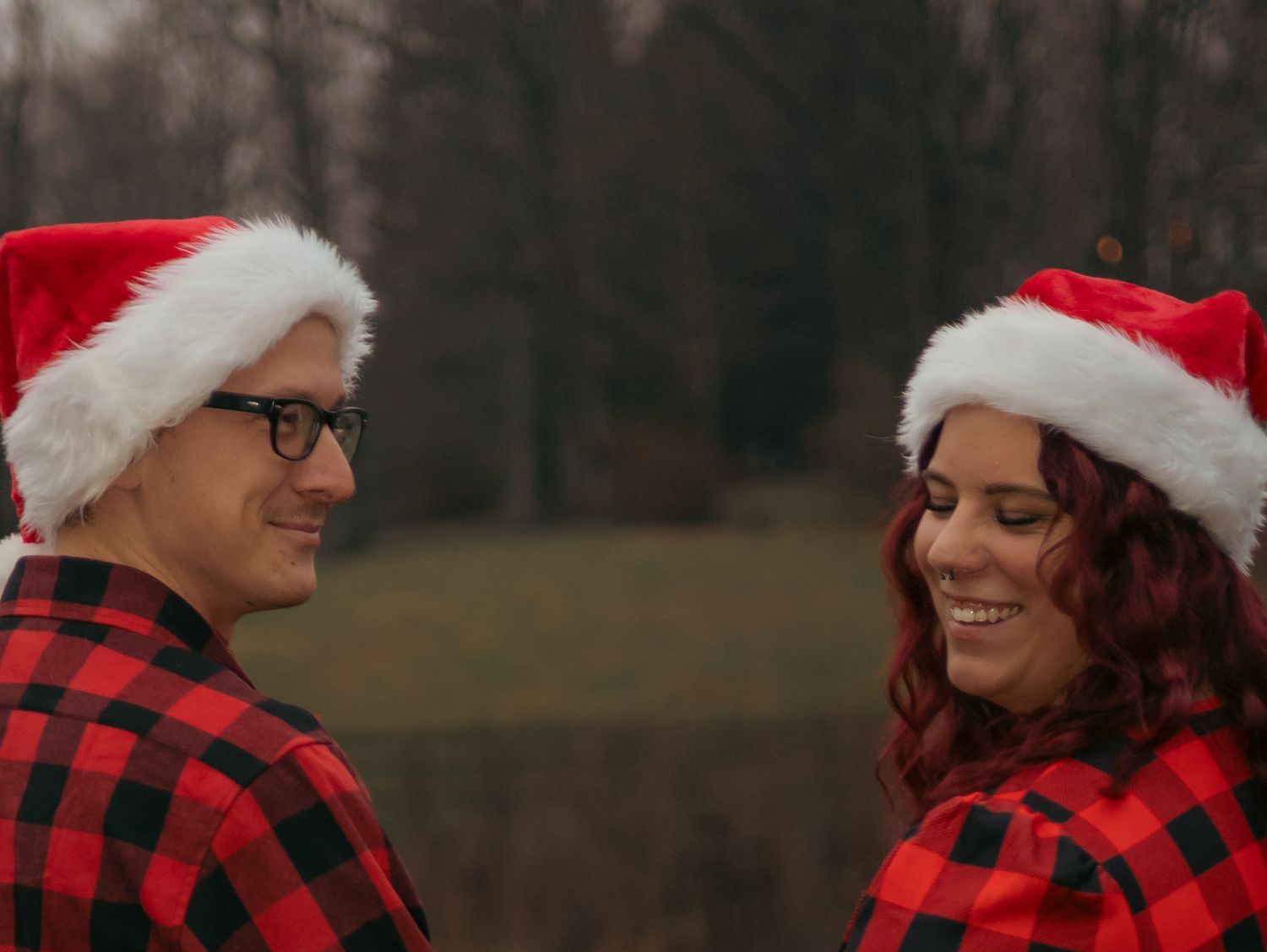 A candid holiday moment between two people in matching buffalo plaid and Santa hats.