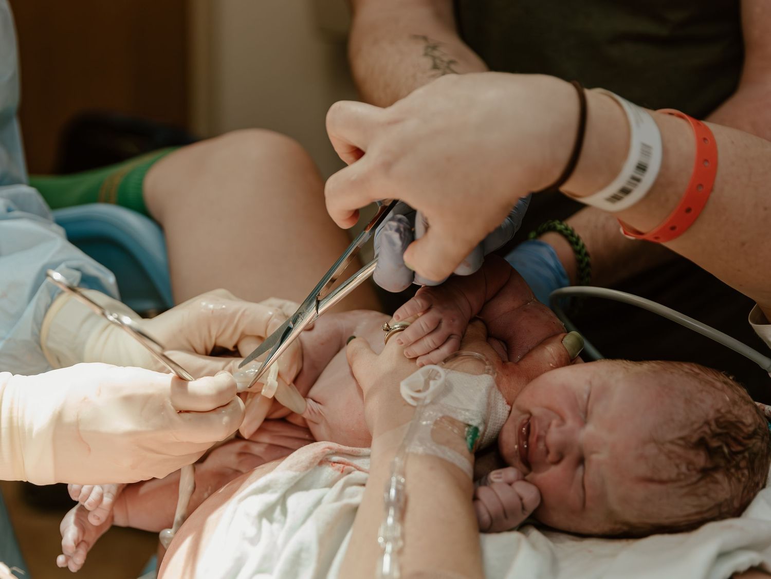 Medical team examining newborn baby in hospital delivery room shortly after birth.