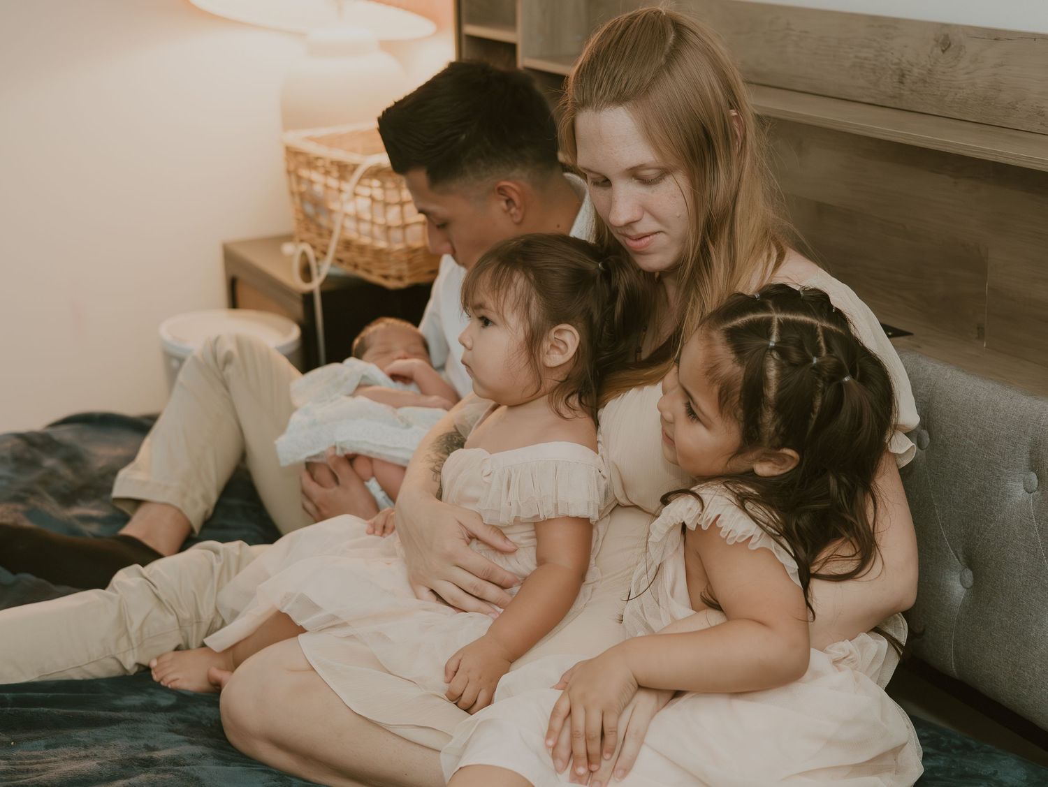 A family sits together on a couch in soft, warm lighting, sharing an intimate moment of togetherness.