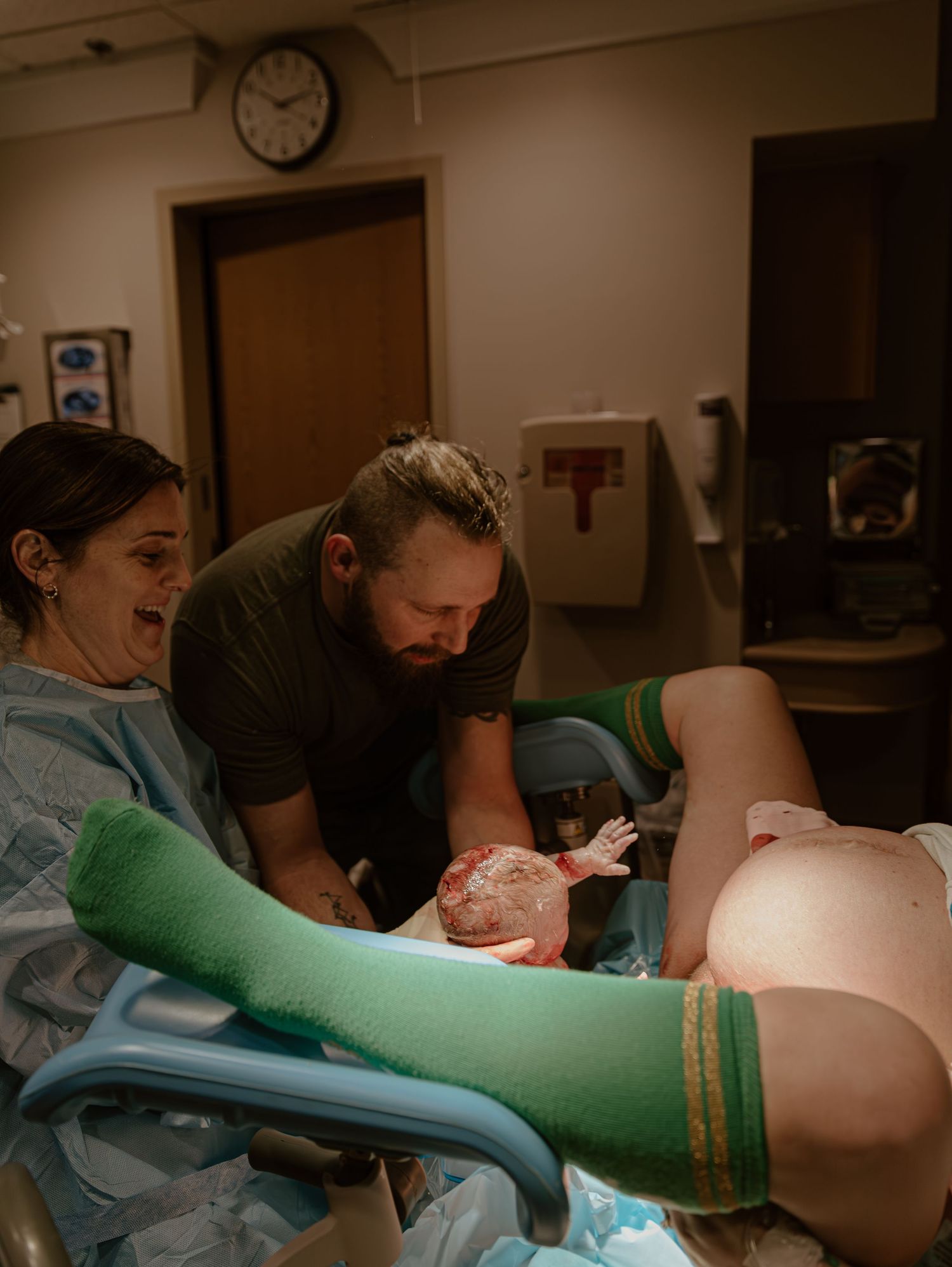 Medical professionals in scrubs perform a medical procedure in a clinical setting while gloved hands assist.
