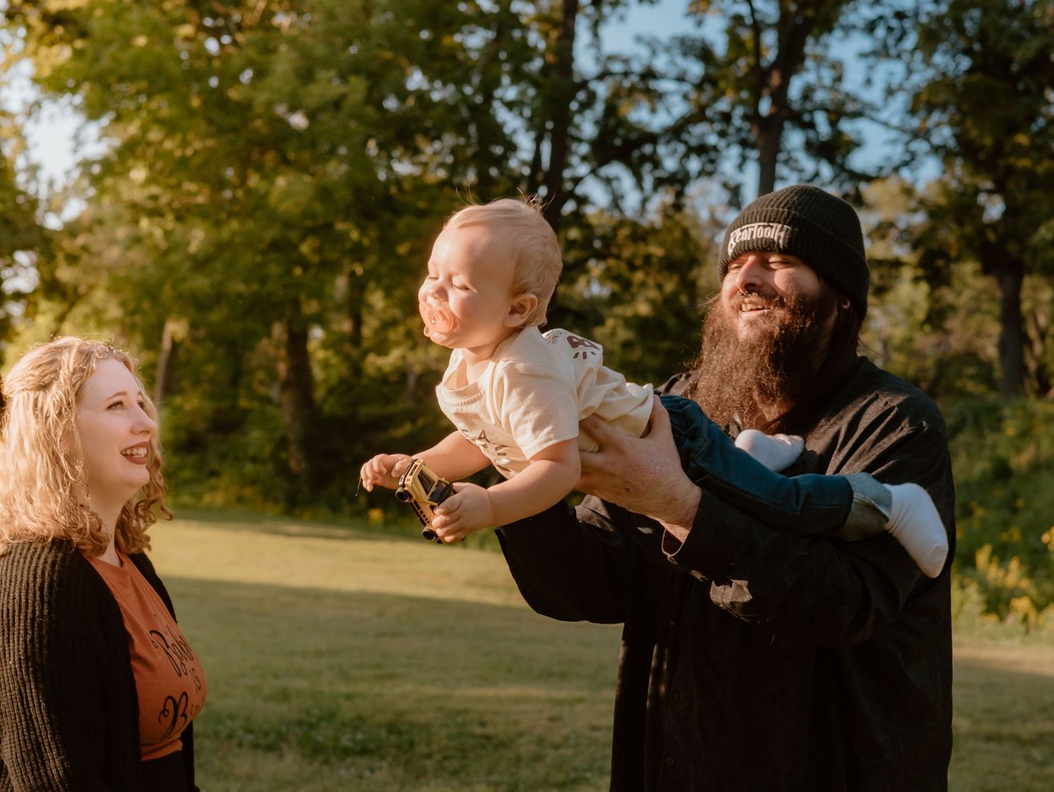 Family members share joyful interactions in a golden-lit park setting.
