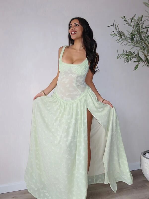 A mint green floral jacquard maxi dress with corset bodice and thigh-high slit shown against white wall and plant decor.