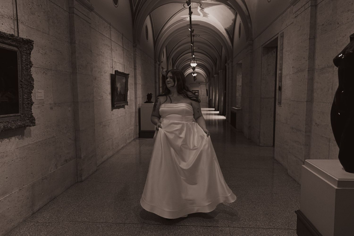 Long hallway with dramatic lighting features arched ceiling and stone walls.
