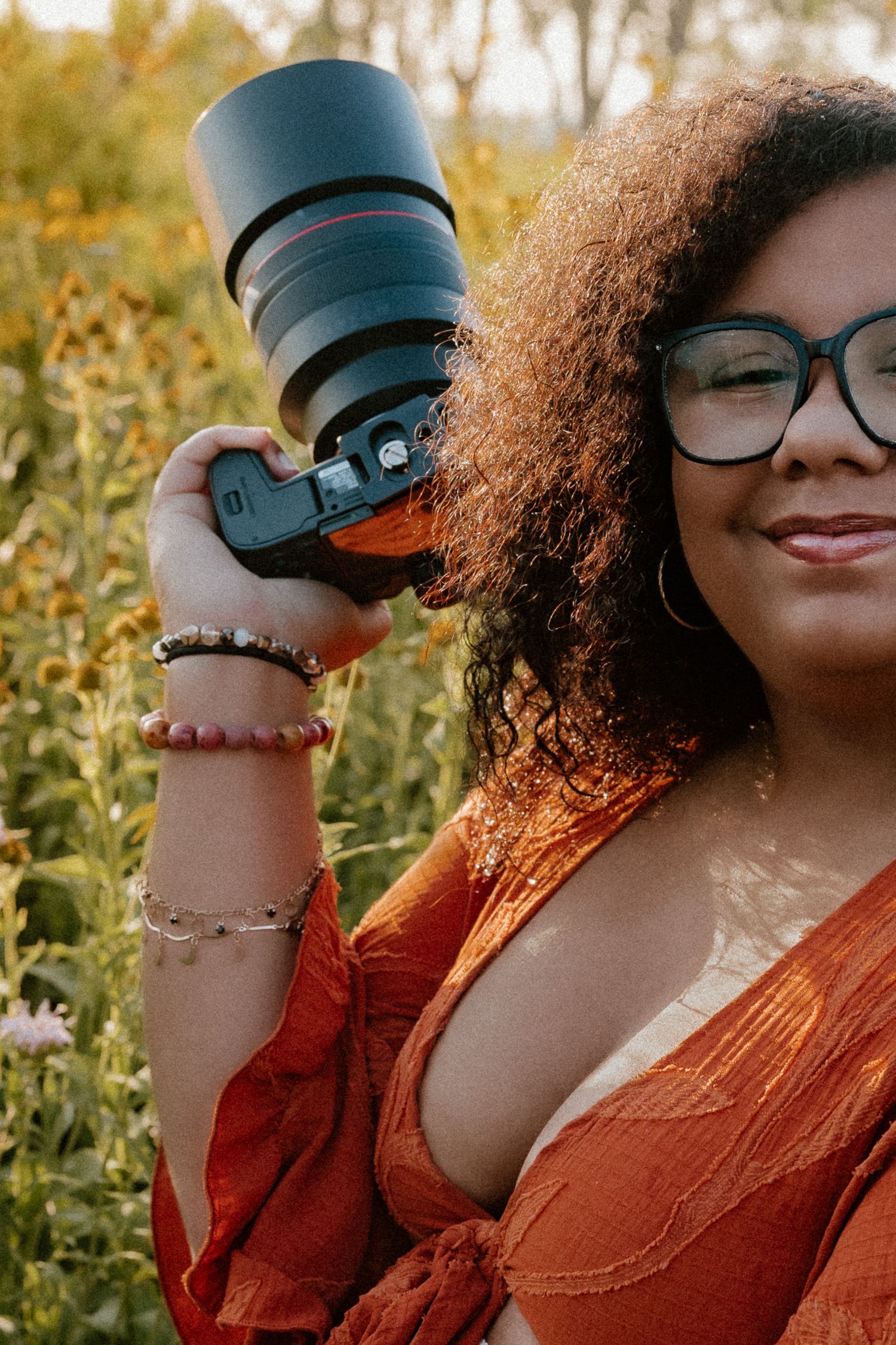 A series of warm-toned outdoor portraits showing someone in orange clothing and curly hair taking photos with a camera.