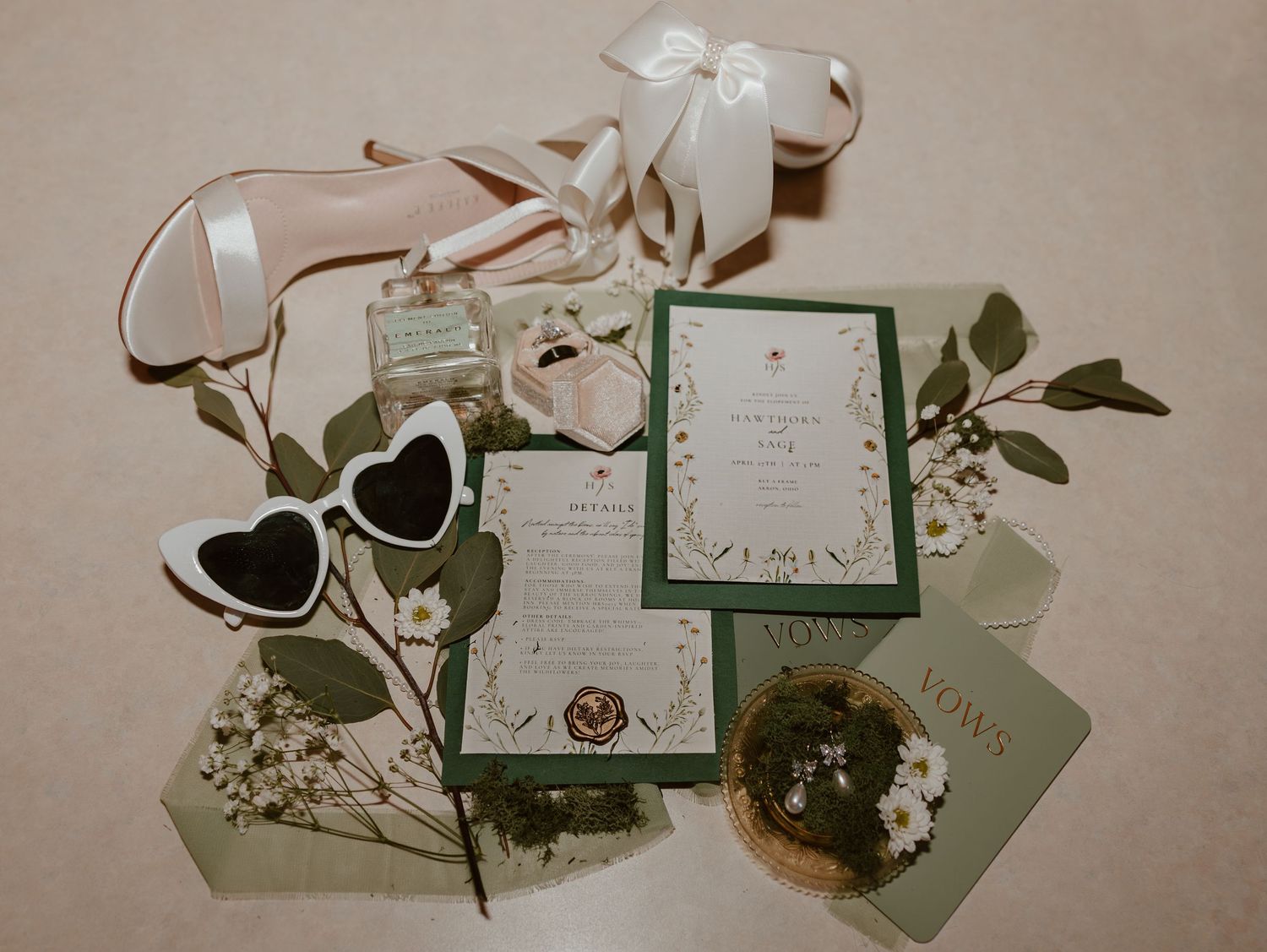 Multiple wedding invitations with floral details and white ribbons arranged on a beige surface with decorative elements.
