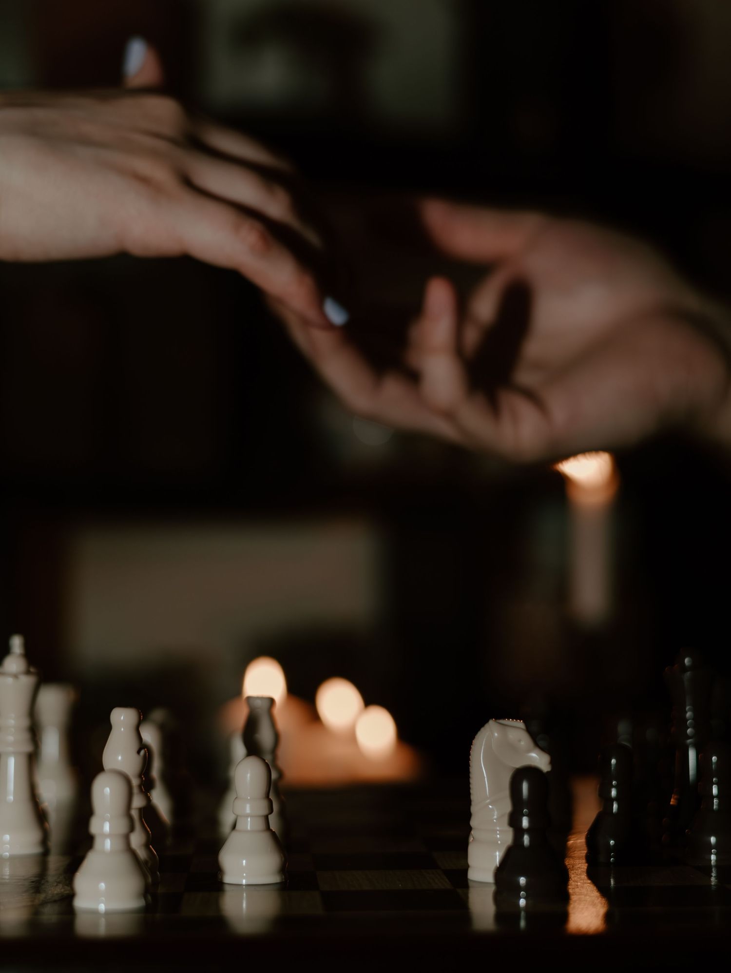 A dramatic close-up of chess pieces on a board with soft bokeh lighting in the background.