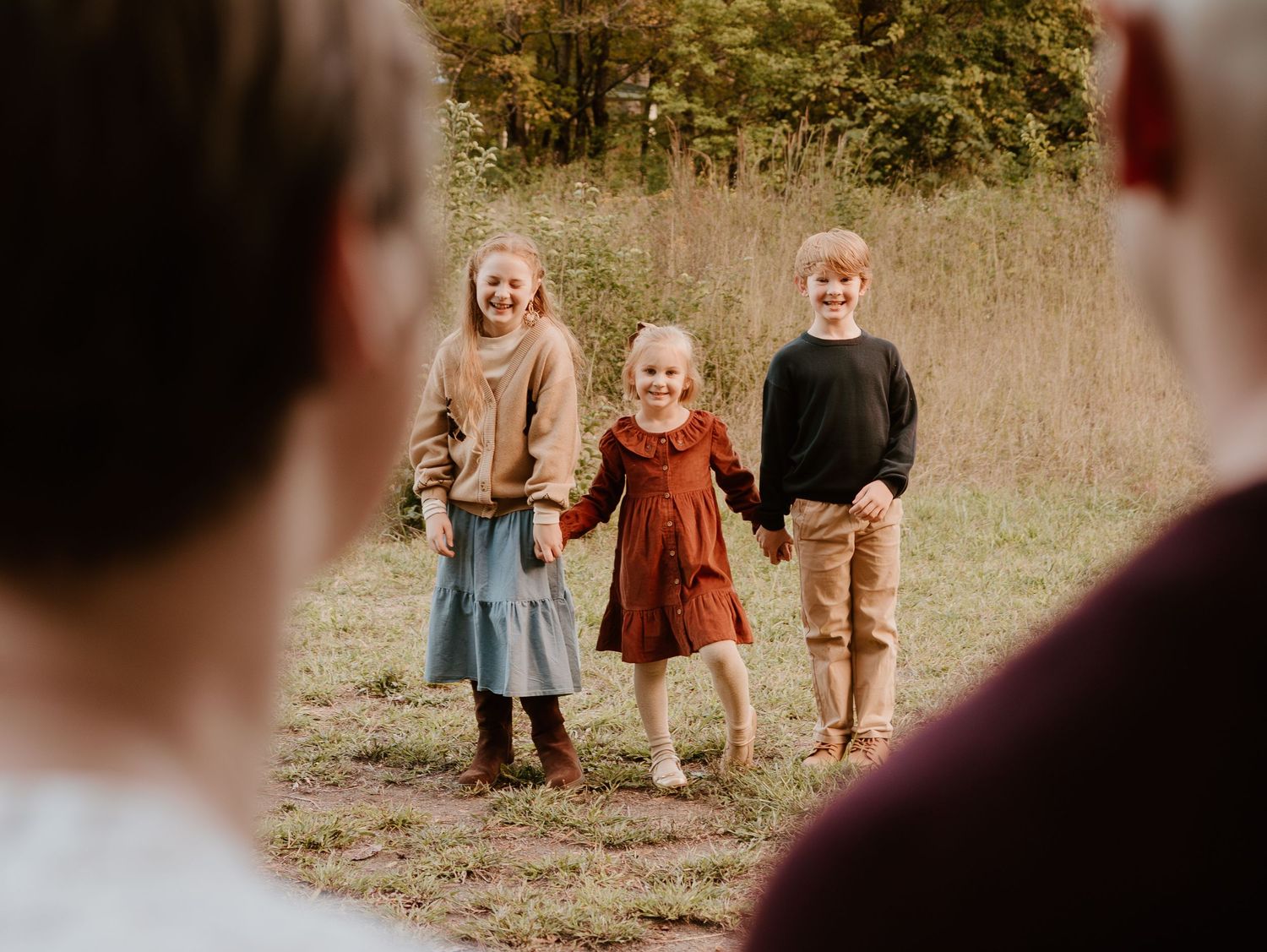 A family walking together through a golden autumn field during a lifestyle photography session.