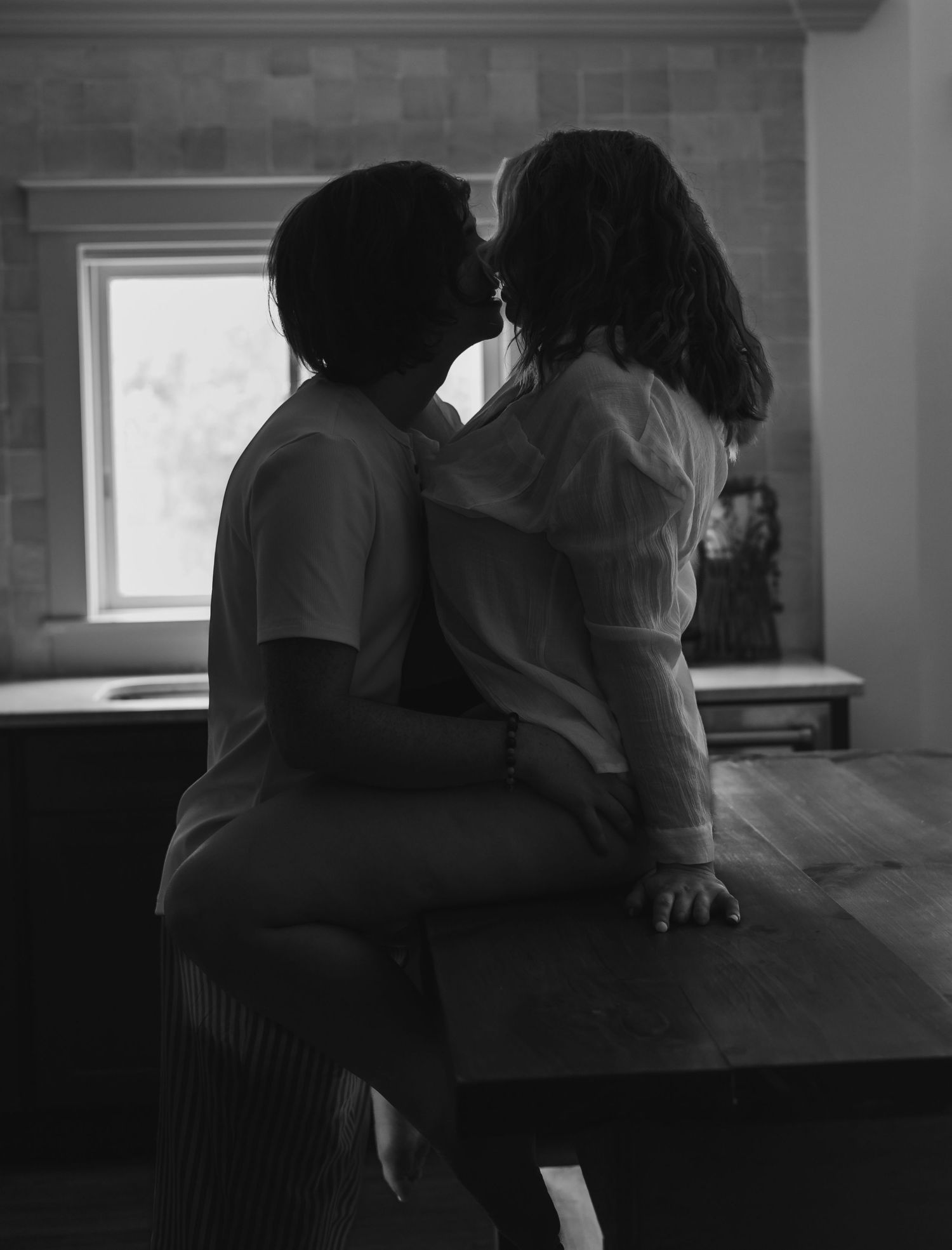 Intimate black and white photo series showing couple embracing in silhouette by window light.