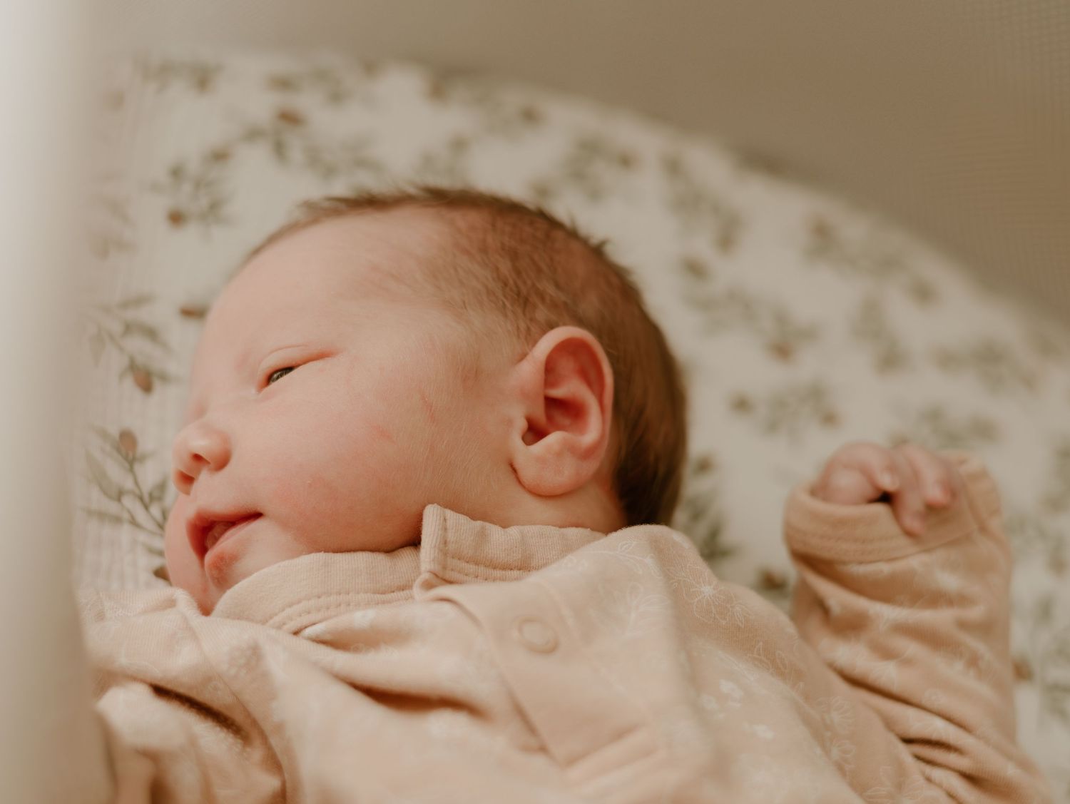 A sleeping newborn baby swaddled in soft pink fabric rests peacefully in a series of gentle poses.