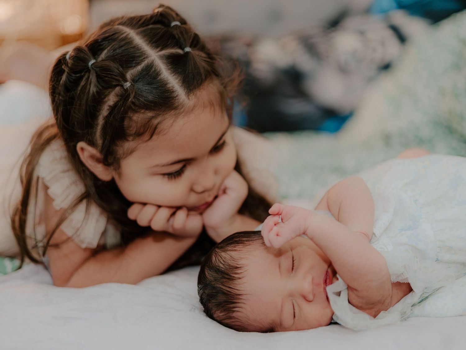 Four connected photos show an infant sleeping peacefully in soft white bedding with sunlit lighting.