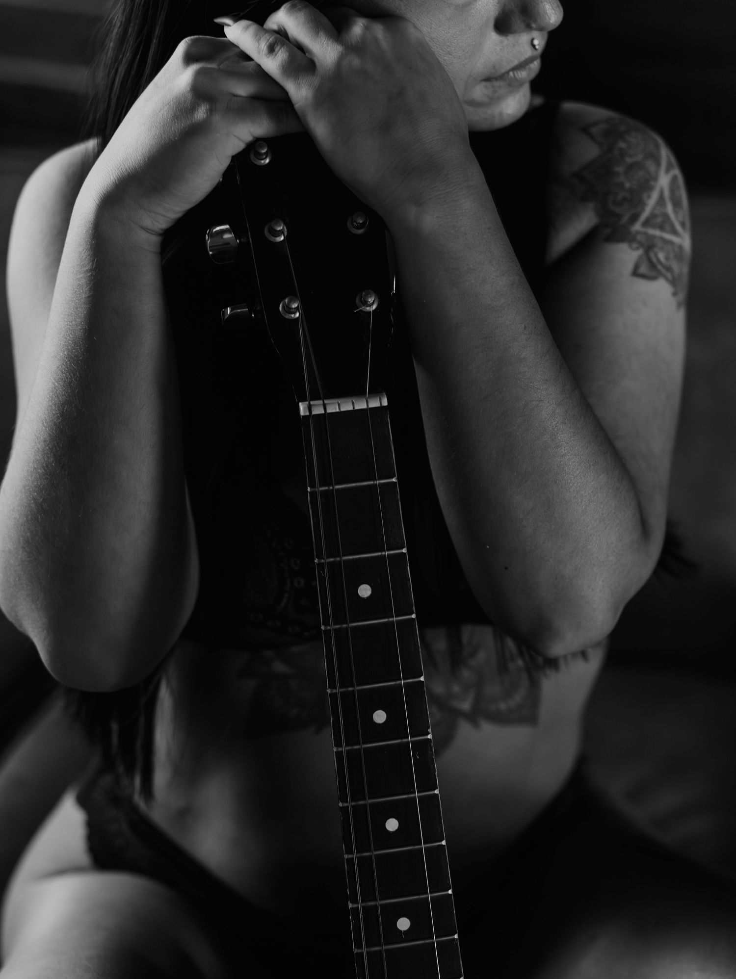 A series of atmospheric black and white photographs showing close-up details of hands playing a guitar neck with frets.