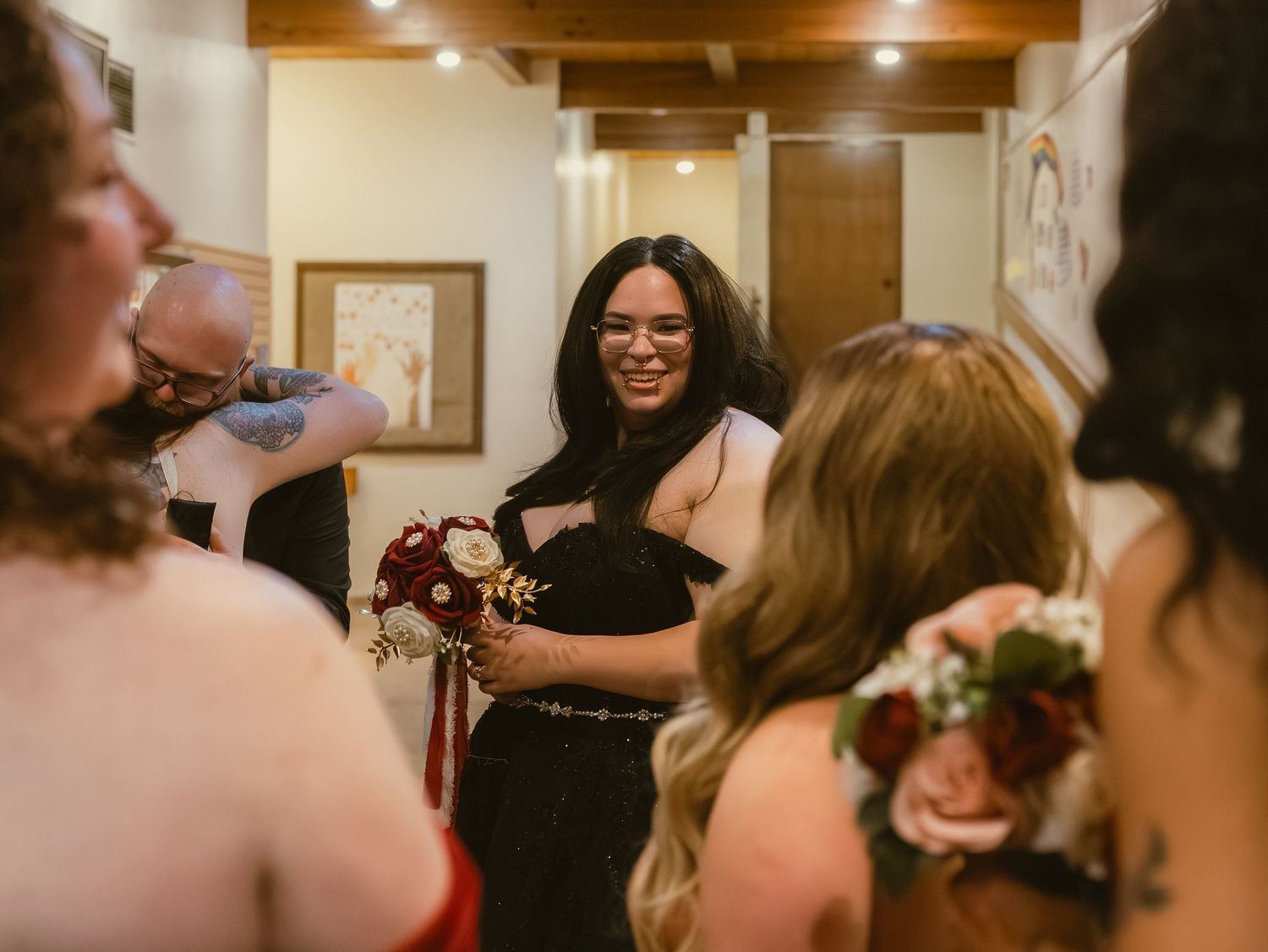 Bride smiling and sharing boutonnieres with bridesmaids in elegant wedding preparation room.
