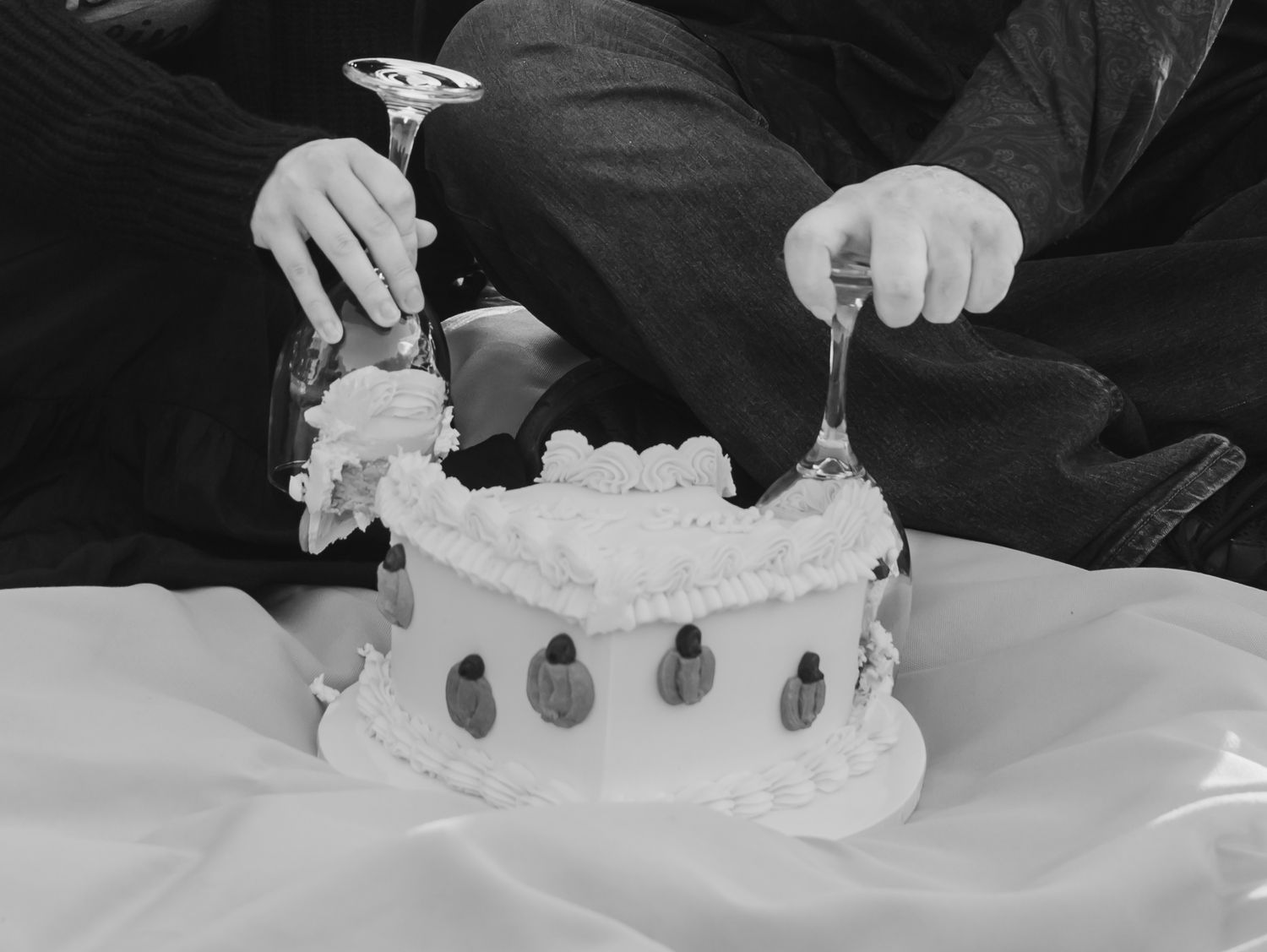 Step by step process of decorating a white cake with frosting and adding small decorative elements on top.