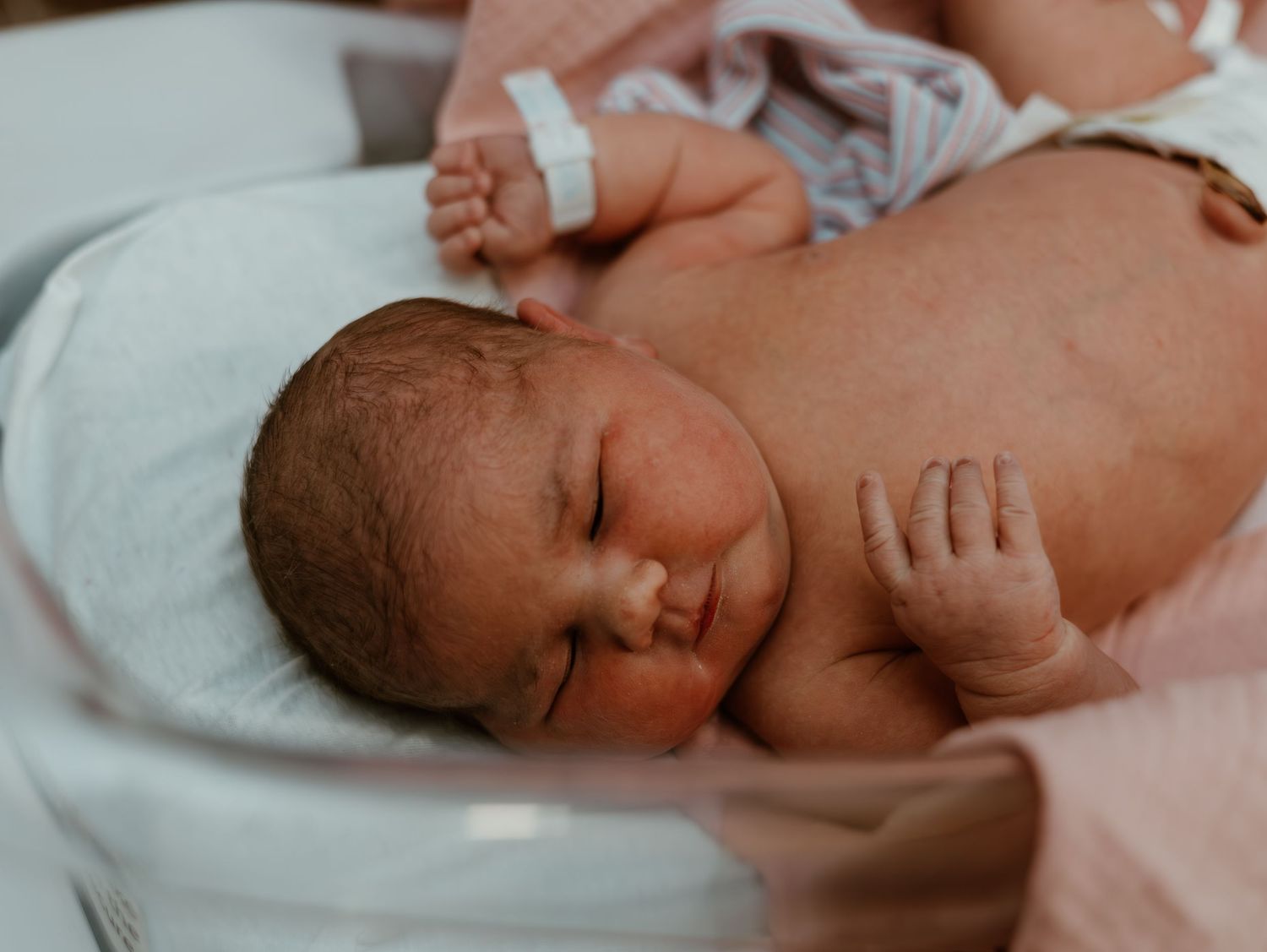A newborn baby lies peacefully sleeping on white bedding in a series of connected photos.