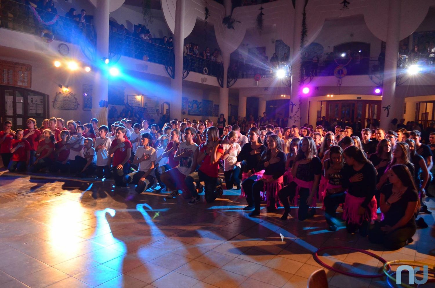 Concert crowd fills a dark venue illuminated by blue and purple stage lights during a live performance.