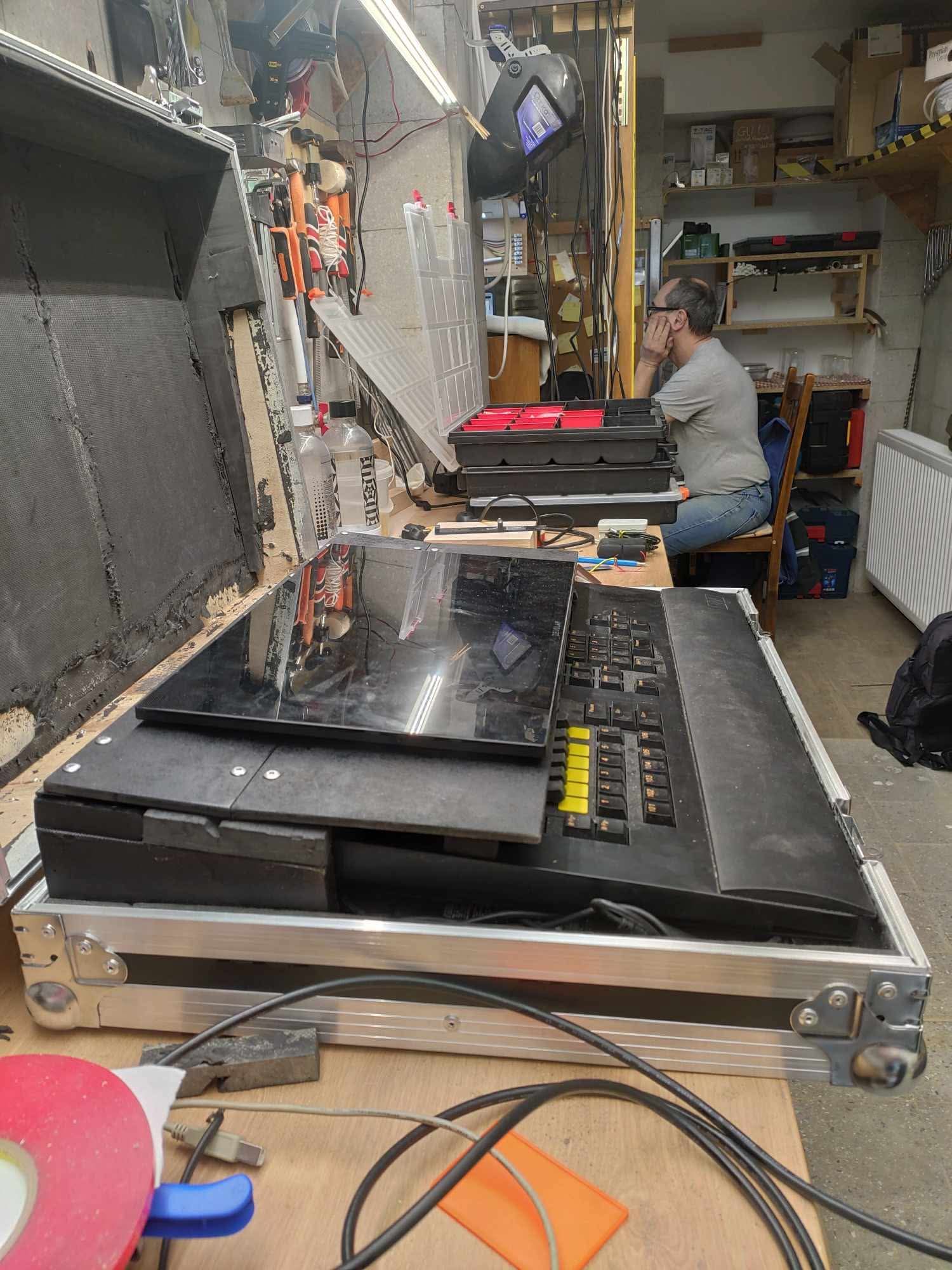 Person working on a Yamaha mixing console undergoing maintenance or repair in a technical workshop environment.