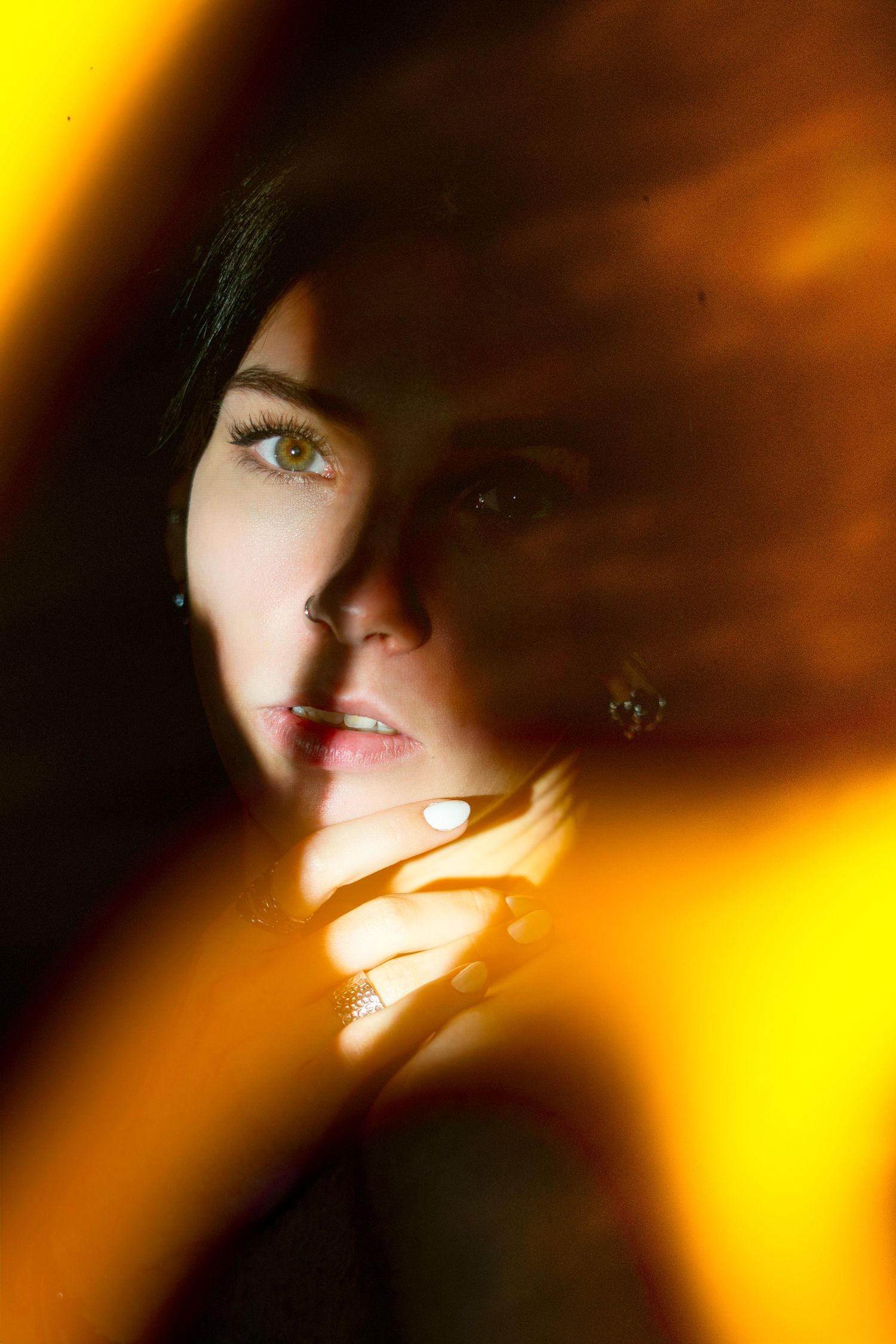Artistic portrait with dramatic lighting showcasing a woman's face illuminated by warm amber tones.