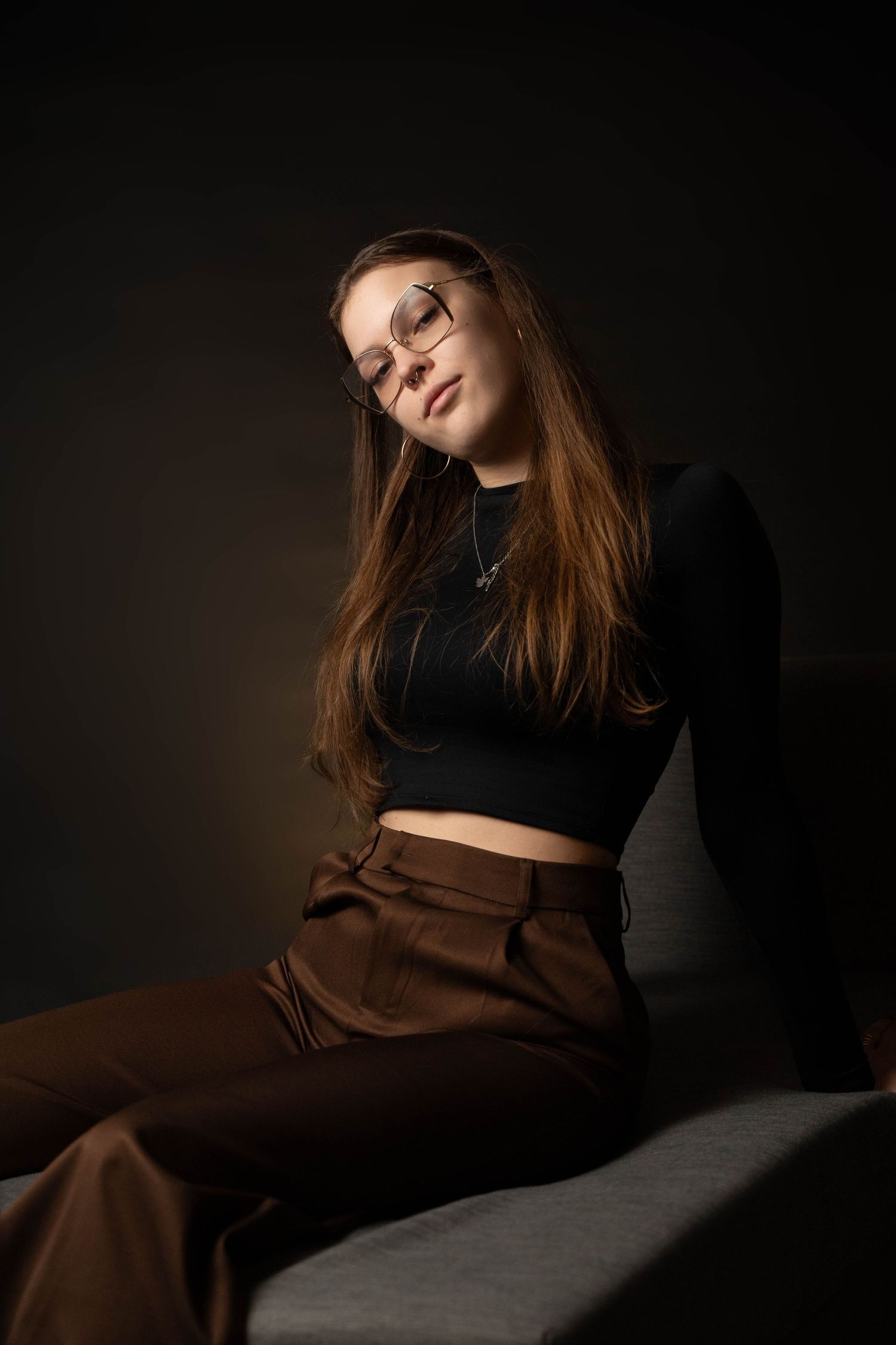 Artistic portrait with brown pants and black top in dramatic lighting.