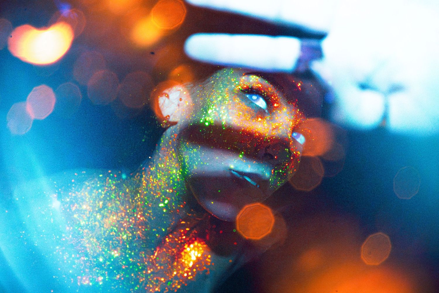 Abstract macro photograph showing colorful bokeh lights and water droplets with orange and blue reflections.