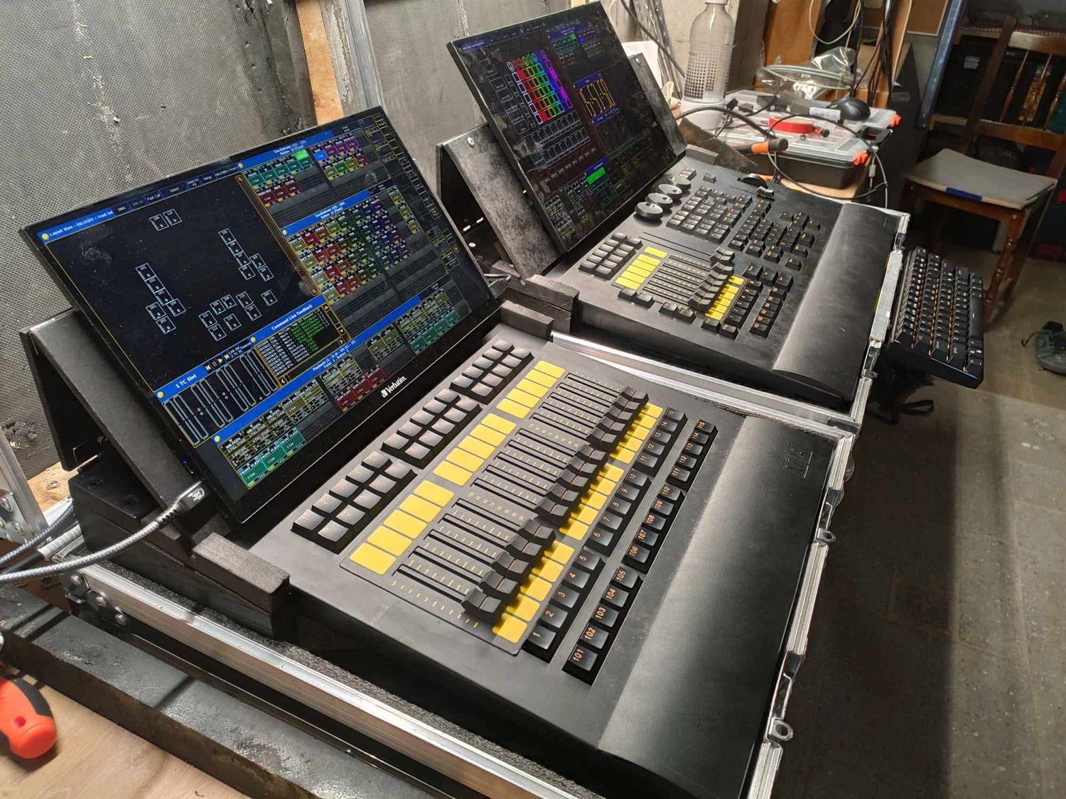 Audio mixing console with illuminated buttons and faders displaying colorful LED screens on a dark background.