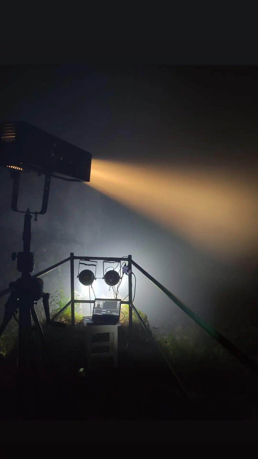 Silhouette of video production equipment and lights against dark background creates dramatic lighting effects.