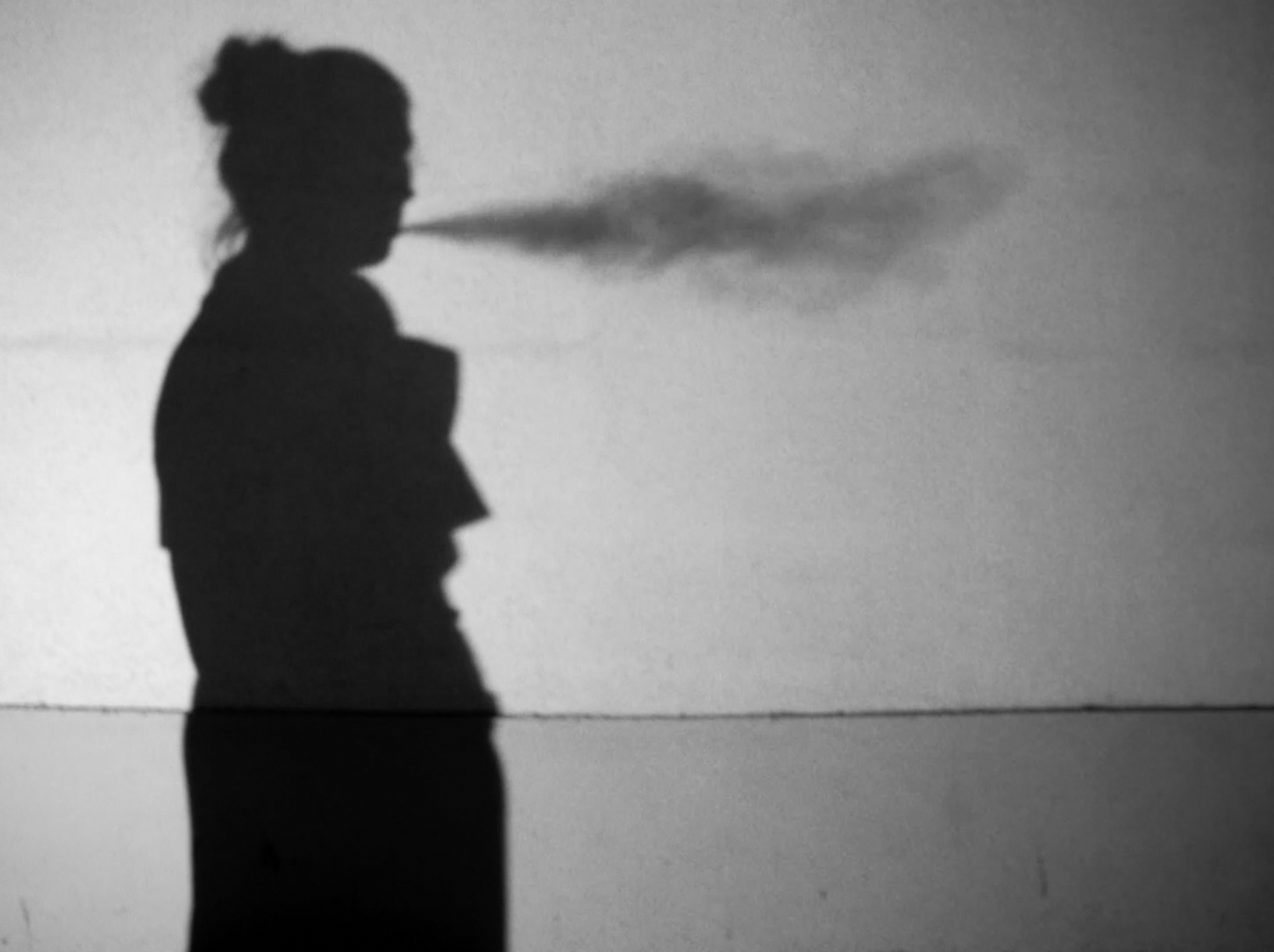 A silhouetted figure stands in dramatic black and white contrast against a minimal background.
