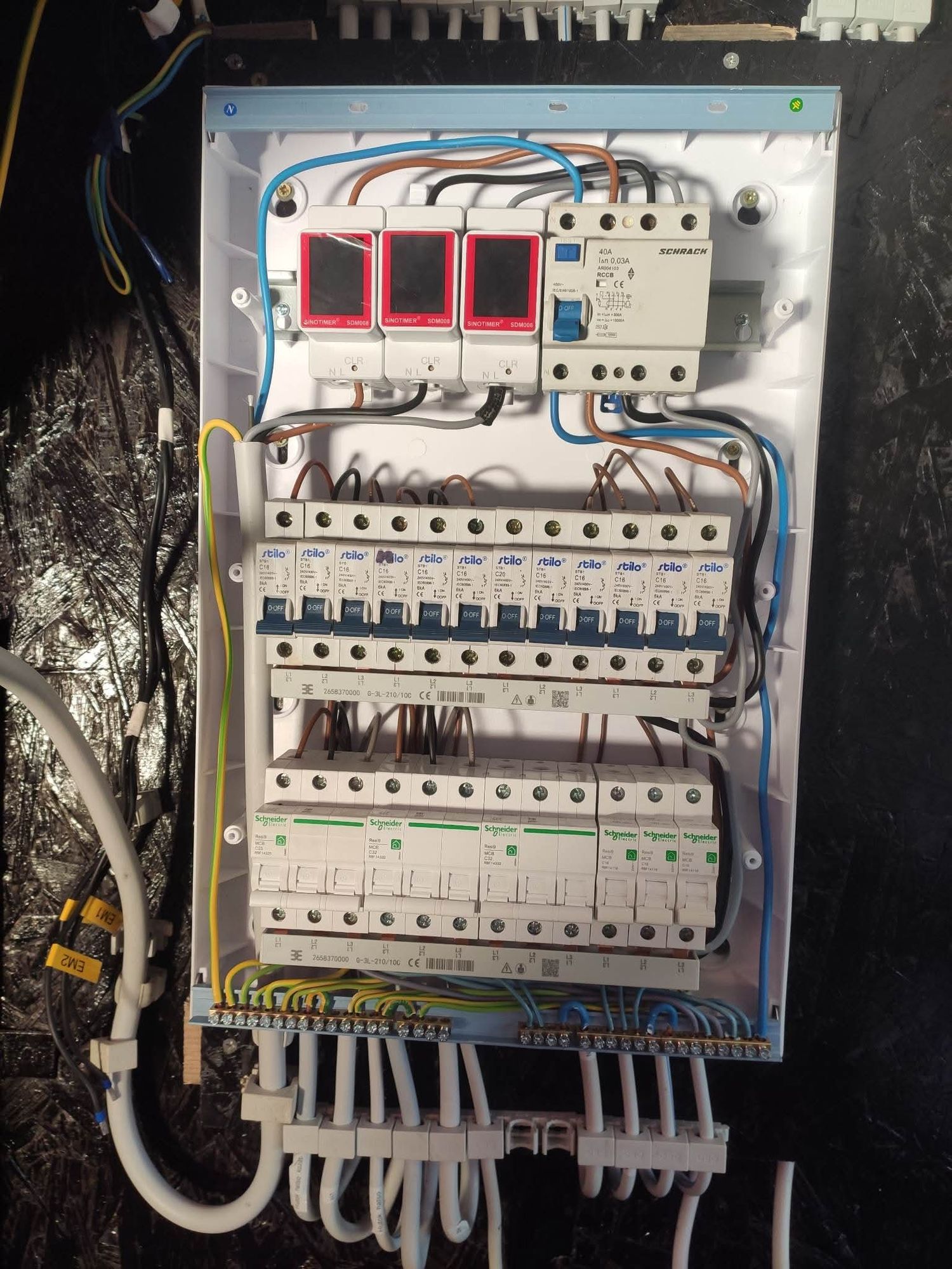 Modern electrical distribution board shows circuit breakers, surge protectors and orderly wiring installation inside panel.