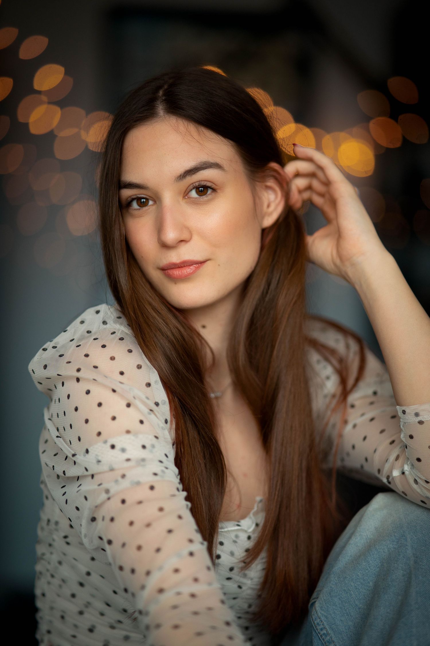 Soft portrait with bokeh lights wearing polka dot sheer top.