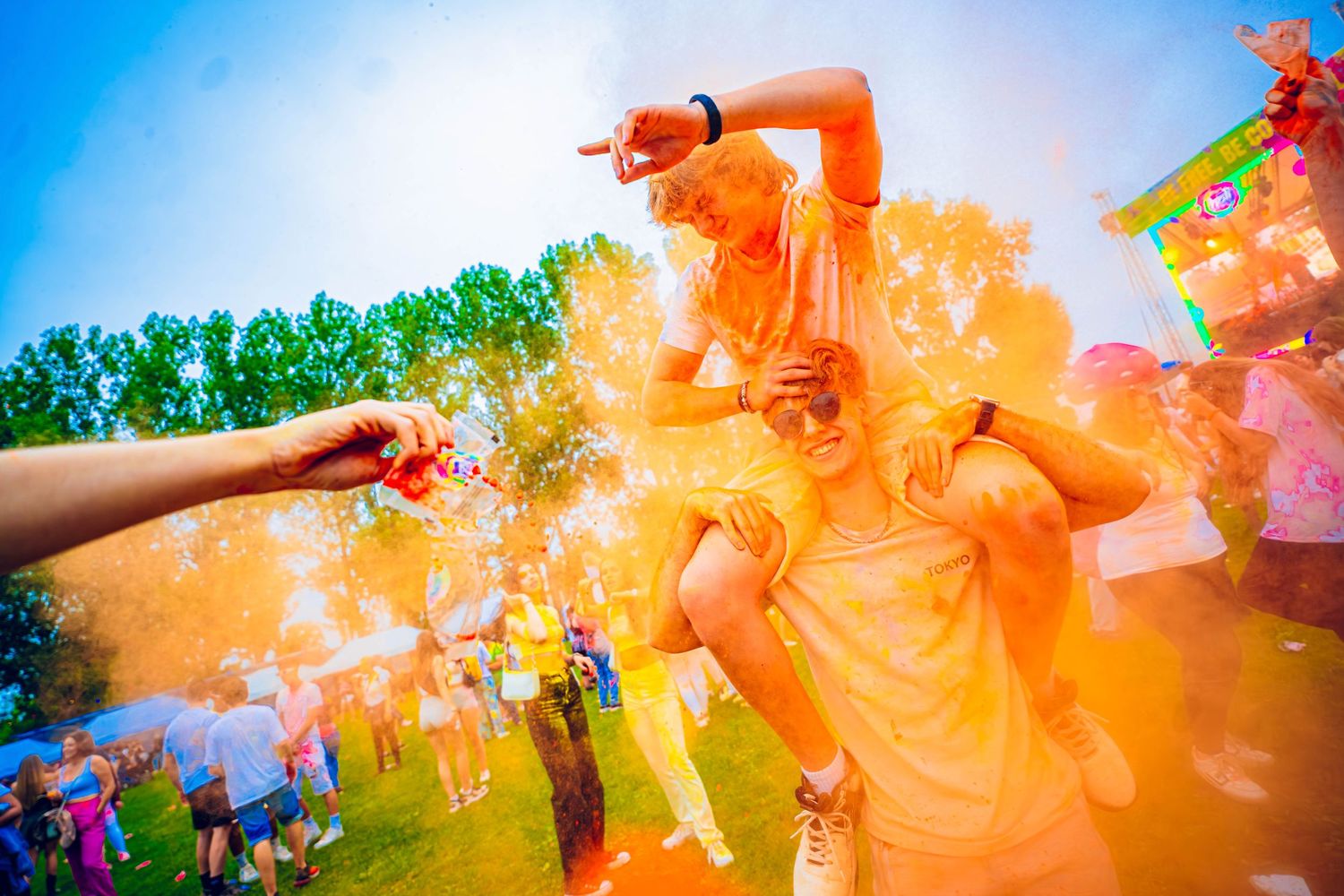 Colorful orange powder being thrown during an outdoor festival celebration.