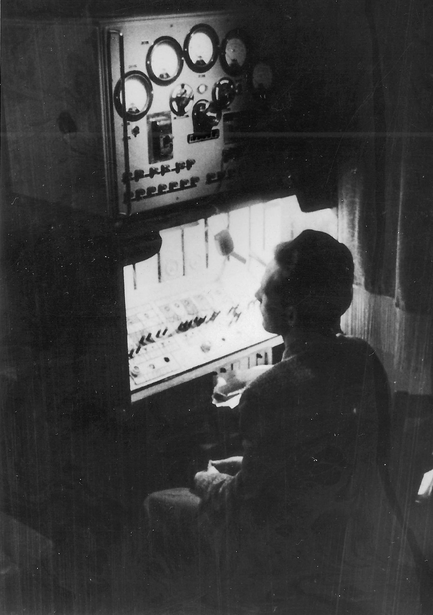 Four grainy black and white photographs showing someone working at a control station with vintage instrument panels.