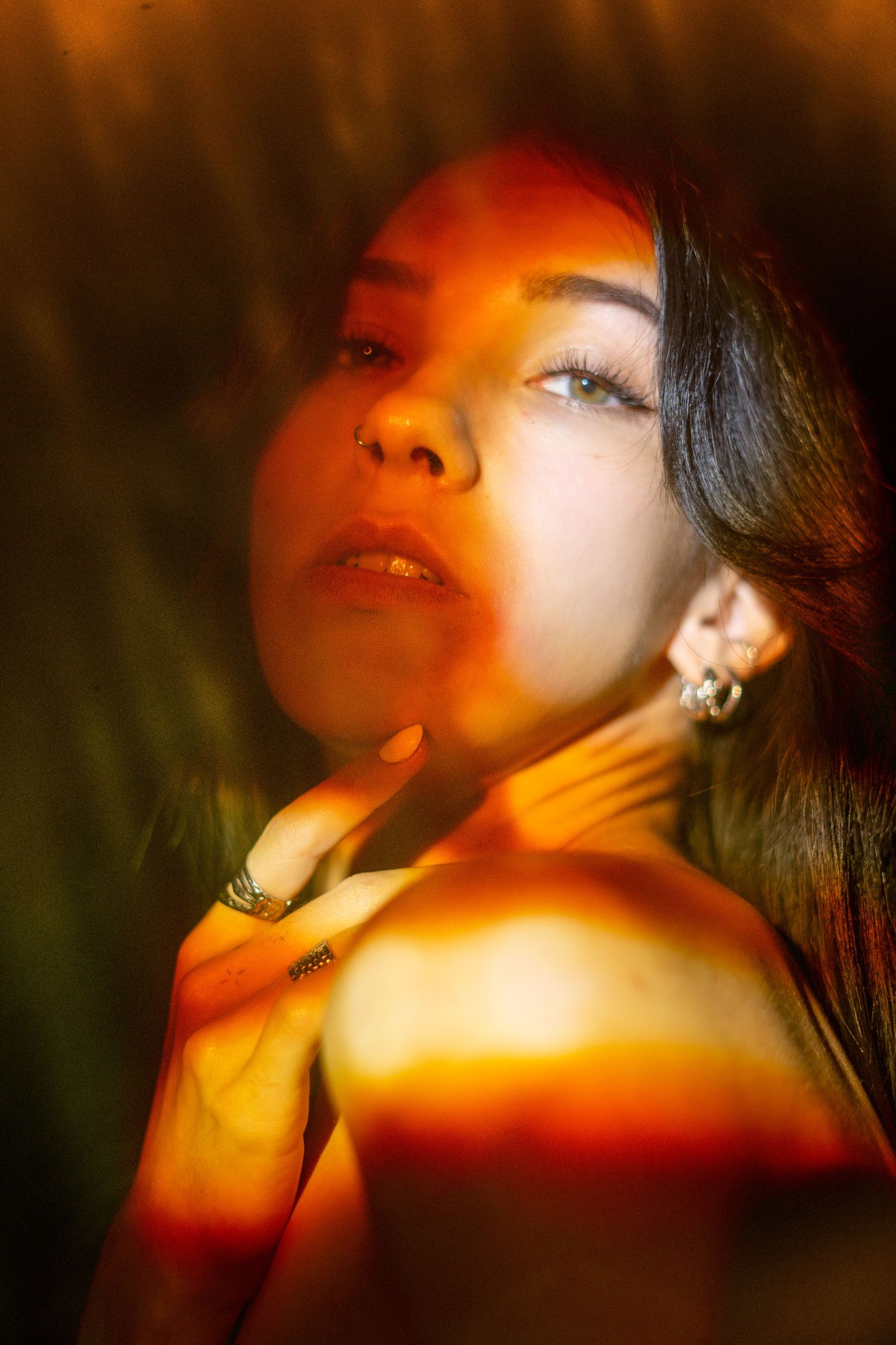 Artistic portrait with warm orange lighting and shadows creating dramatic mood and ambiance.