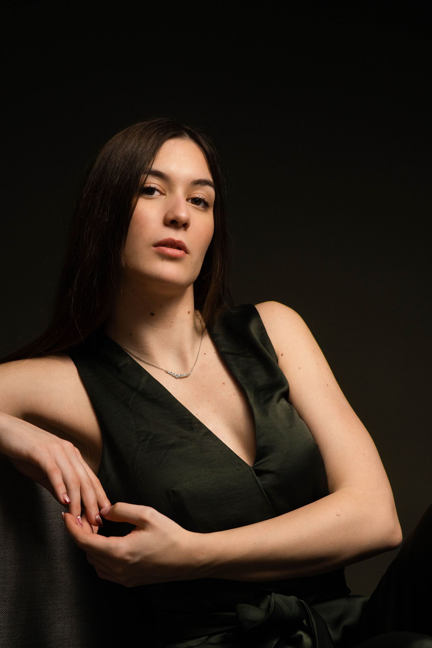 Elegant studio portrait in black dress with moody lighting.