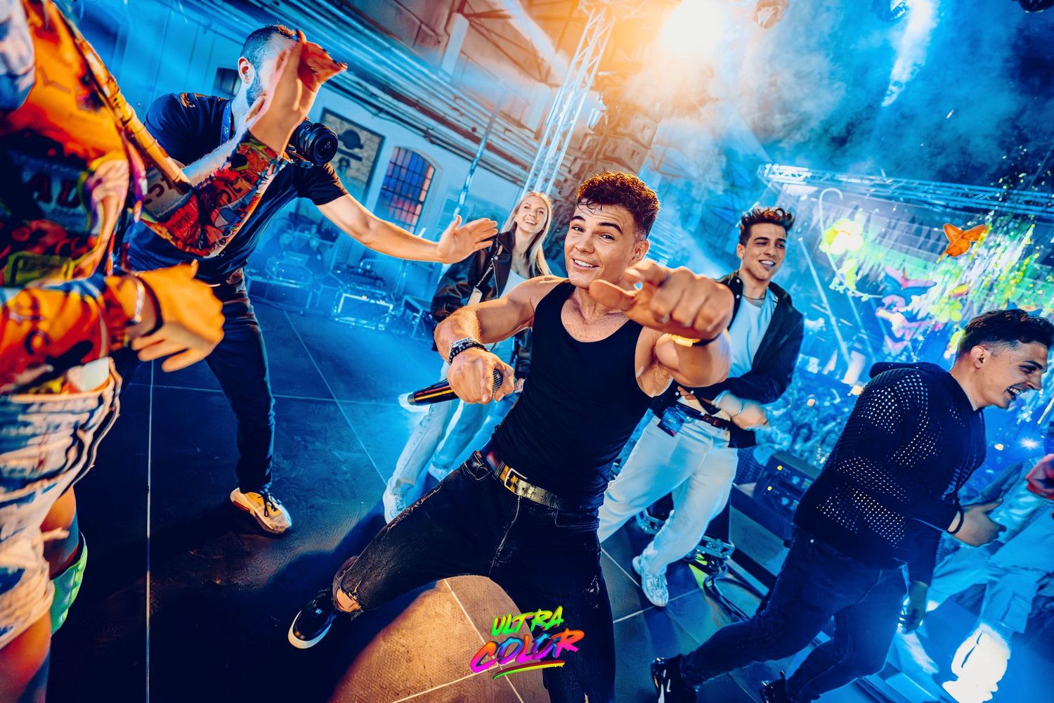 Energetic dance party scene with performers and blue lighting effects.