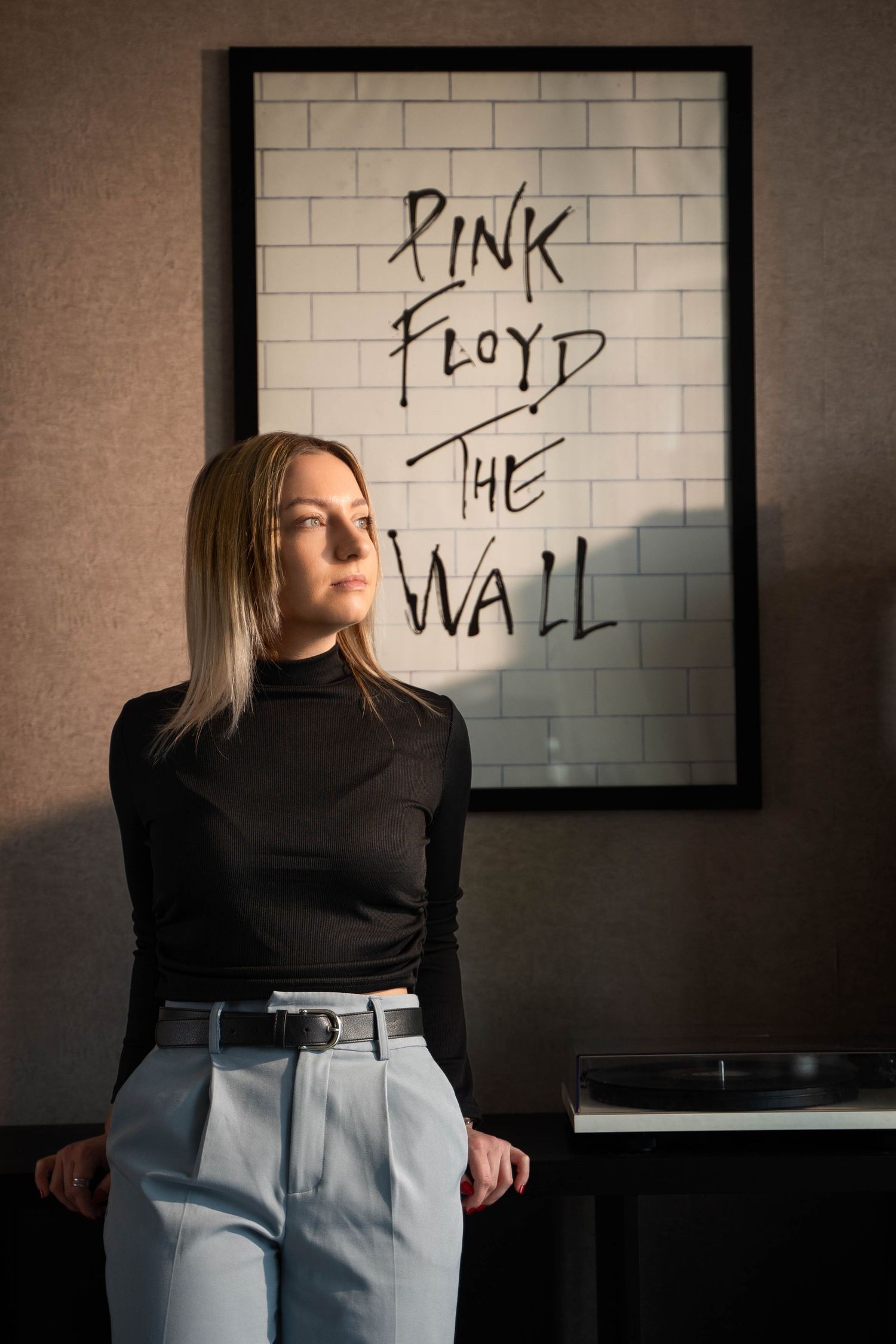 Stylish portrait against Pink Floyd The Wall poster in modern interior.