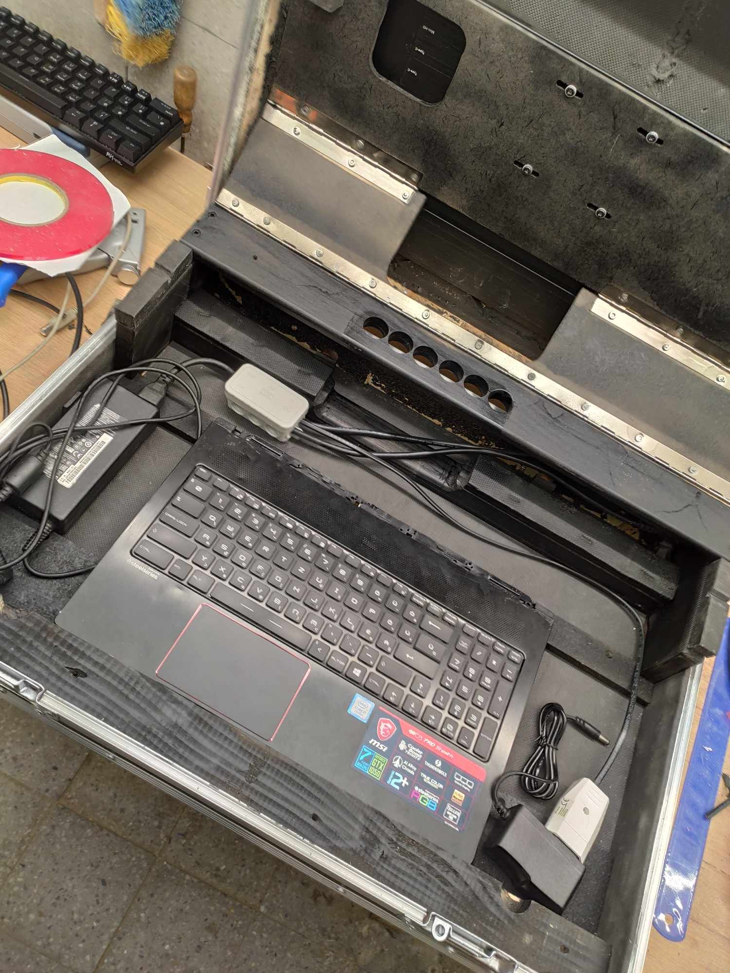 A laptop computer with keyboard and accessories arranged neatly inside a protective hard case.