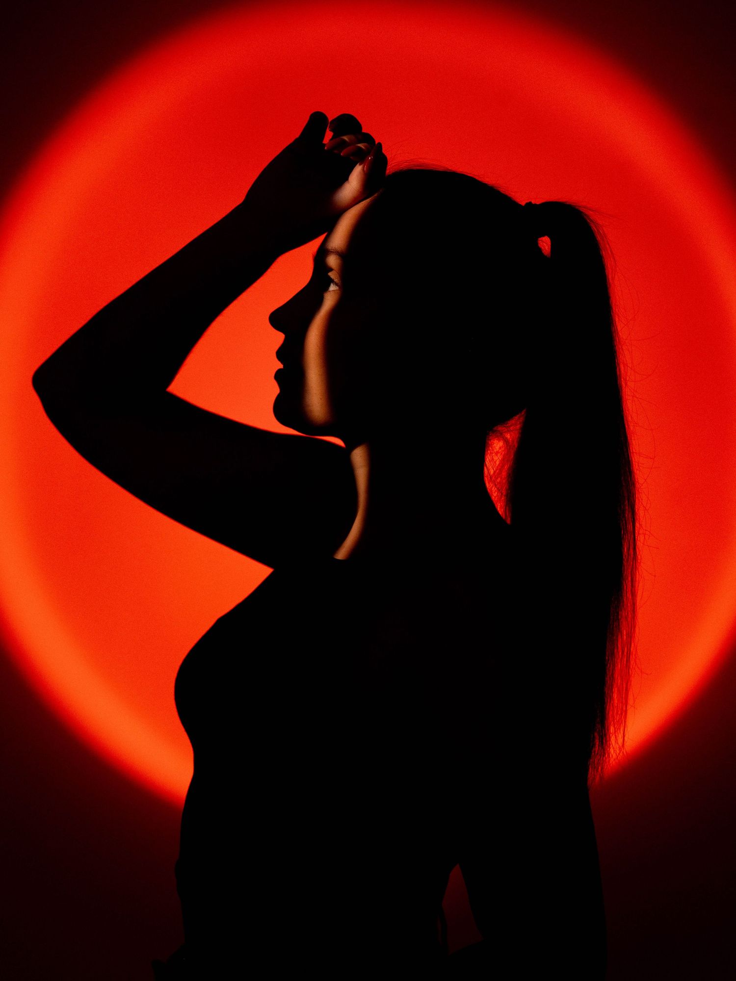Silhouette figure poses against a glowing red circular backdrop creating a striking contrast.