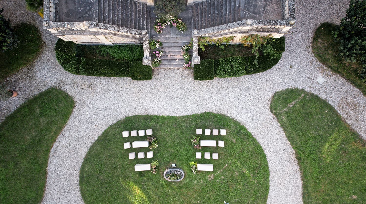 Aerial view of wedding ceremony setup with white chairs arranged in heart shape on manicured lawn.