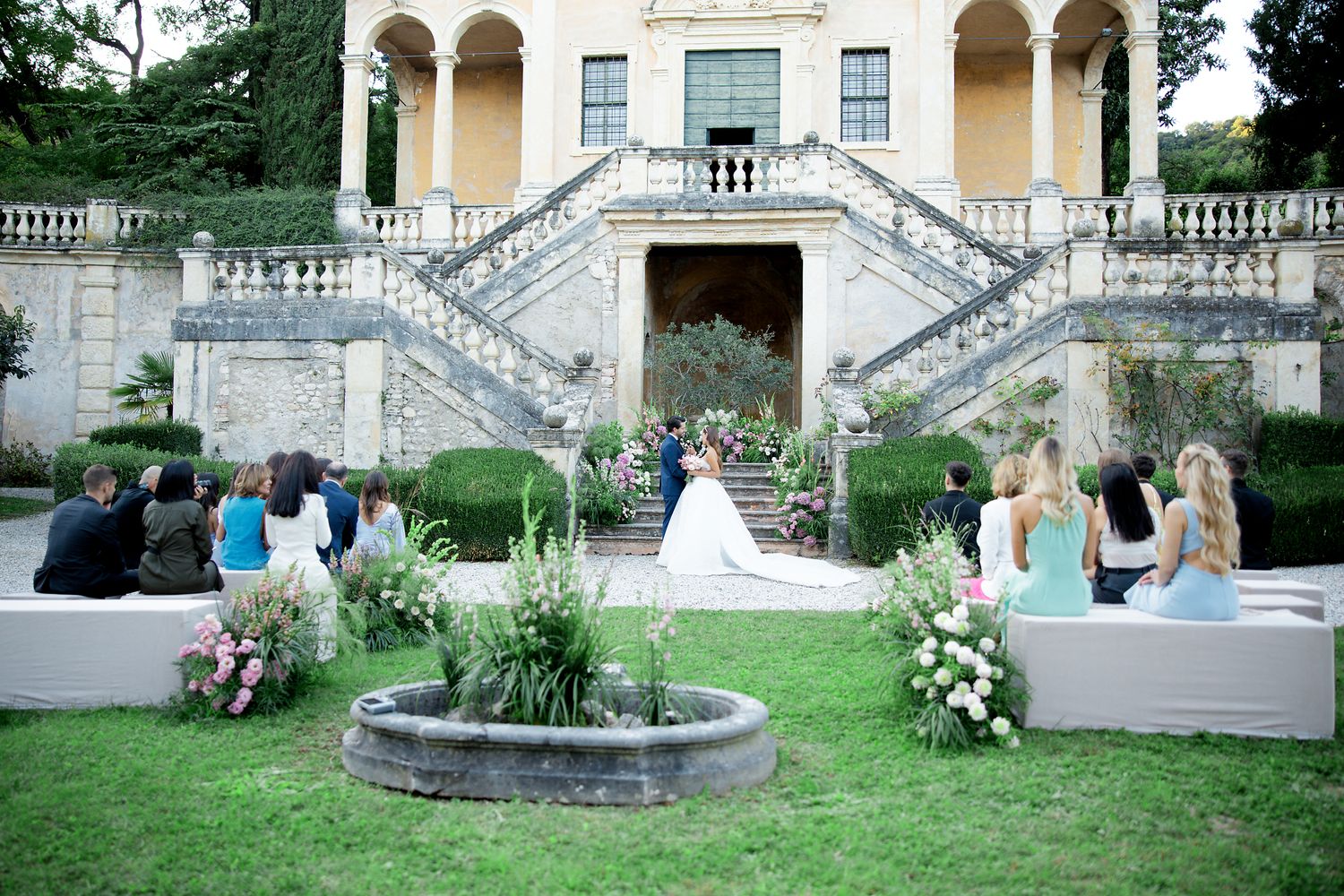 Elegant outdoor wedding ceremony setup with grand staircase and white floral decorations.