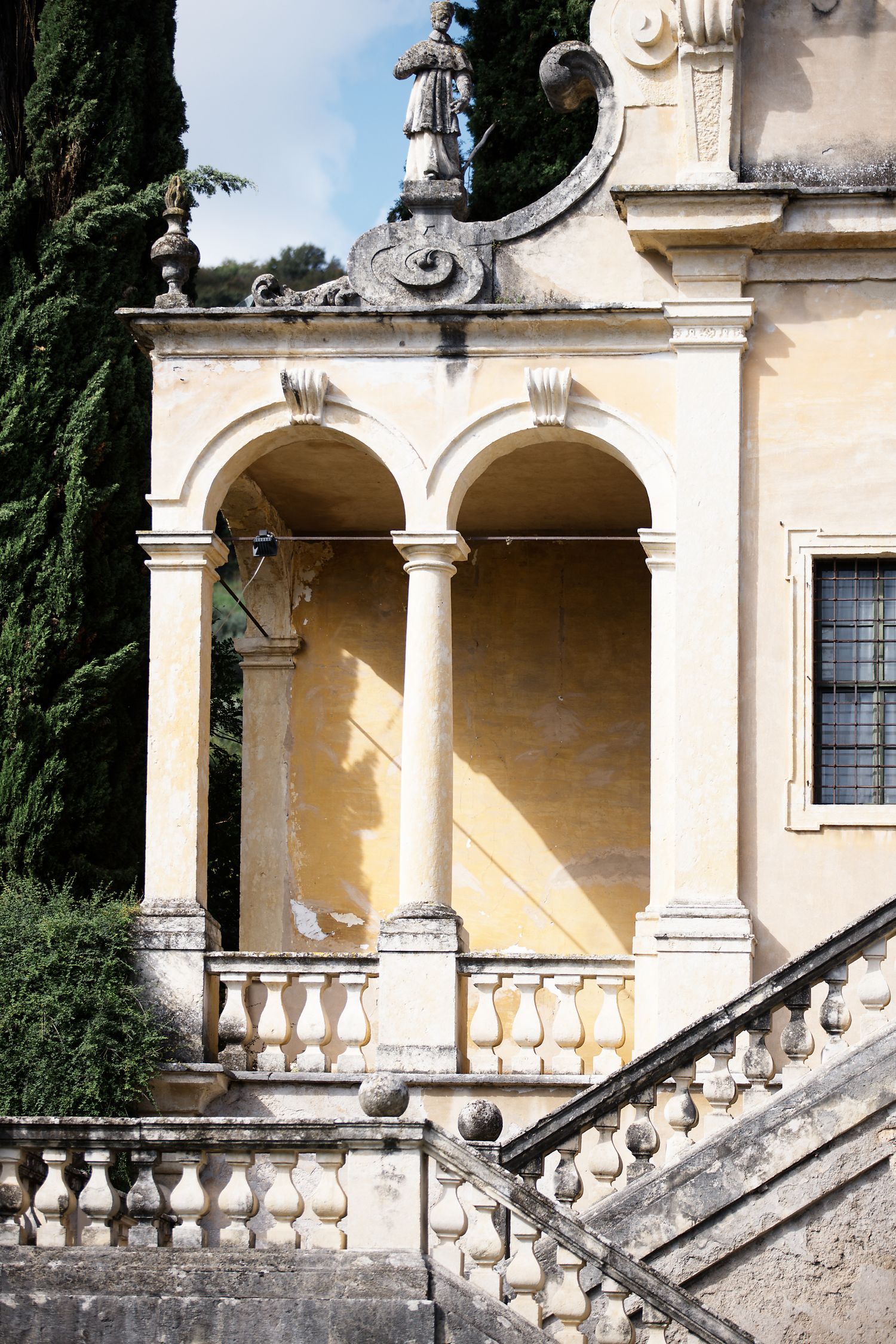Ornate Italian villa entrance with double arches and decorative stone balustrade.